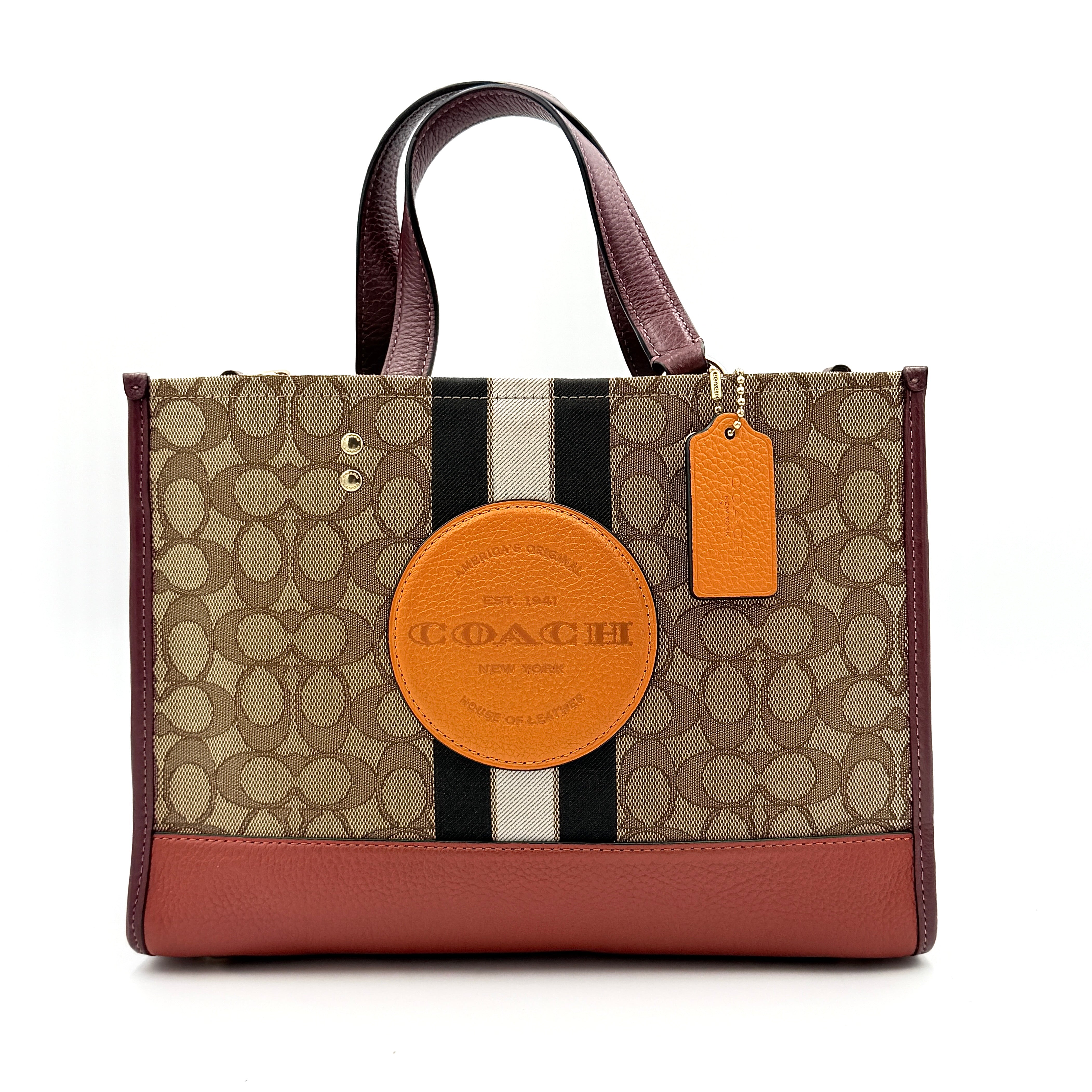 Coach 2Way Signature 22 Dempsey Tote in brown jacquard and burgundy leather with orange logo patch, shown with detachable strap.