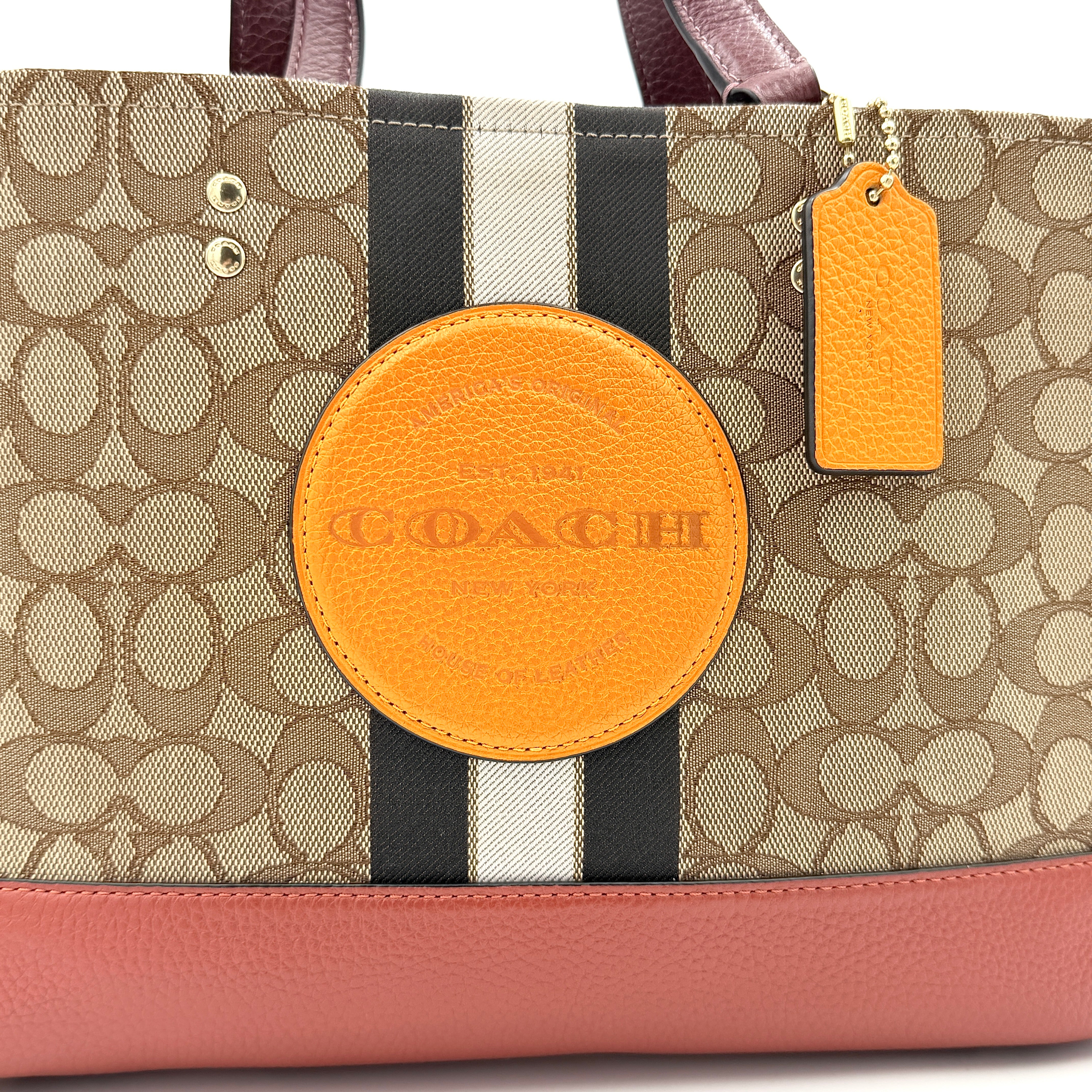 Coach 2Way Signature 22 Dempsey Tote in brown jacquard and burgundy leather with orange logo patch, shown with detachable strap.