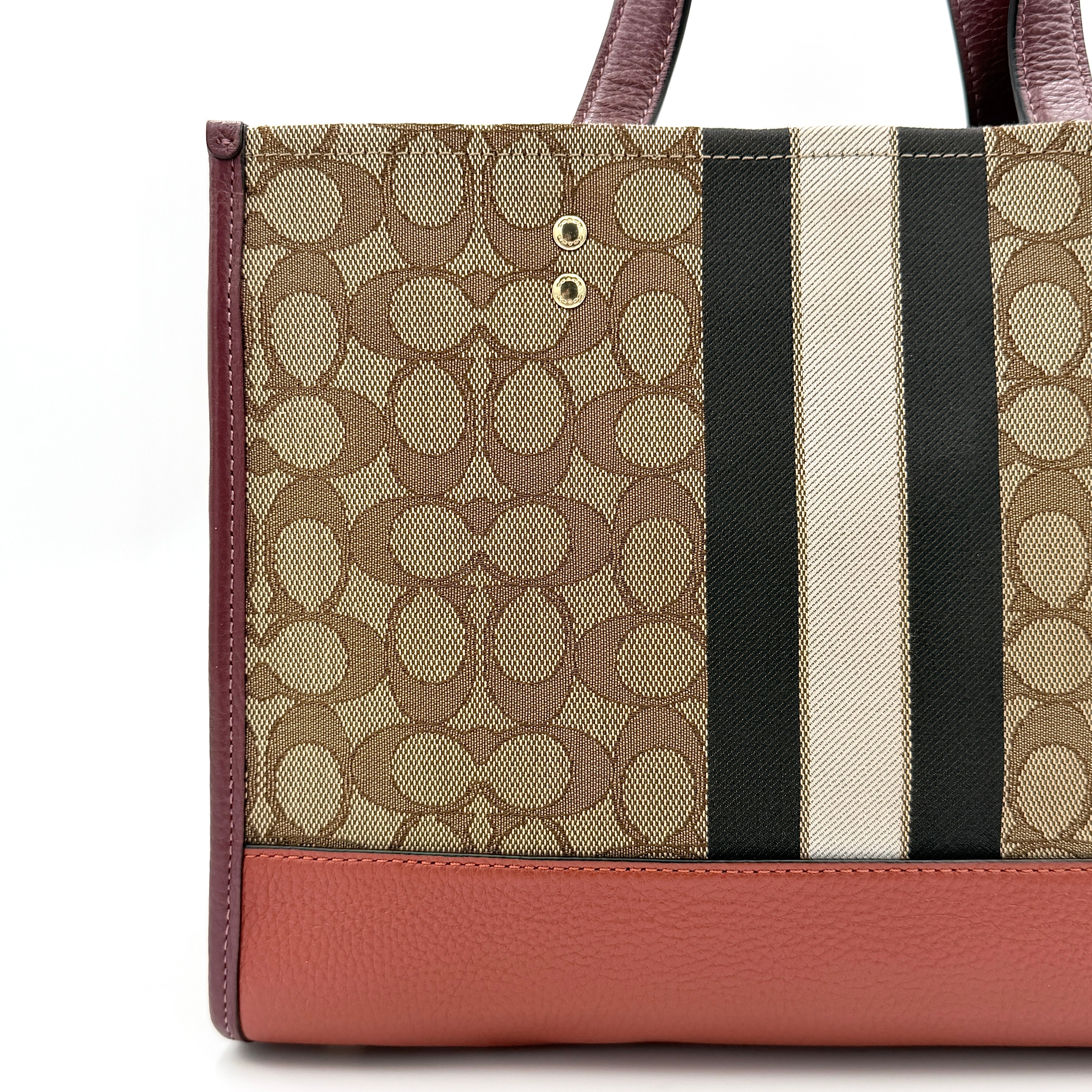 Coach 2Way Signature 22 Dempsey Tote in brown jacquard and burgundy leather with orange logo patch, shown with detachable strap.