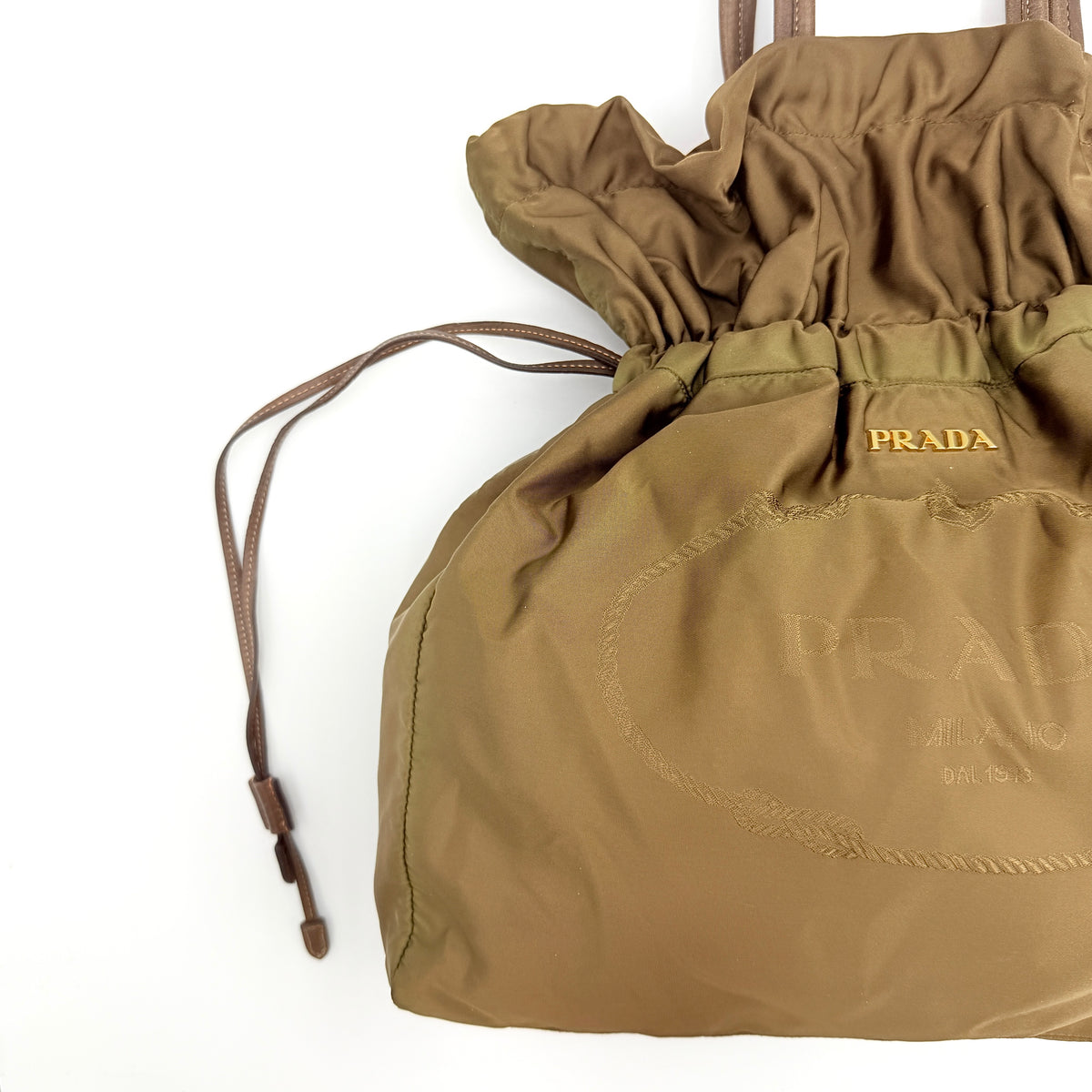 Prada Tessuto brown nylon drawstring shoulder bag with leather handles and gold logo detail, photographed against a white background.