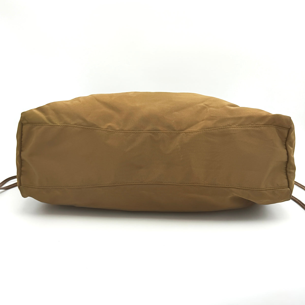 Prada Tessuto brown nylon drawstring shoulder bag with leather handles and gold logo detail, photographed against a white background.