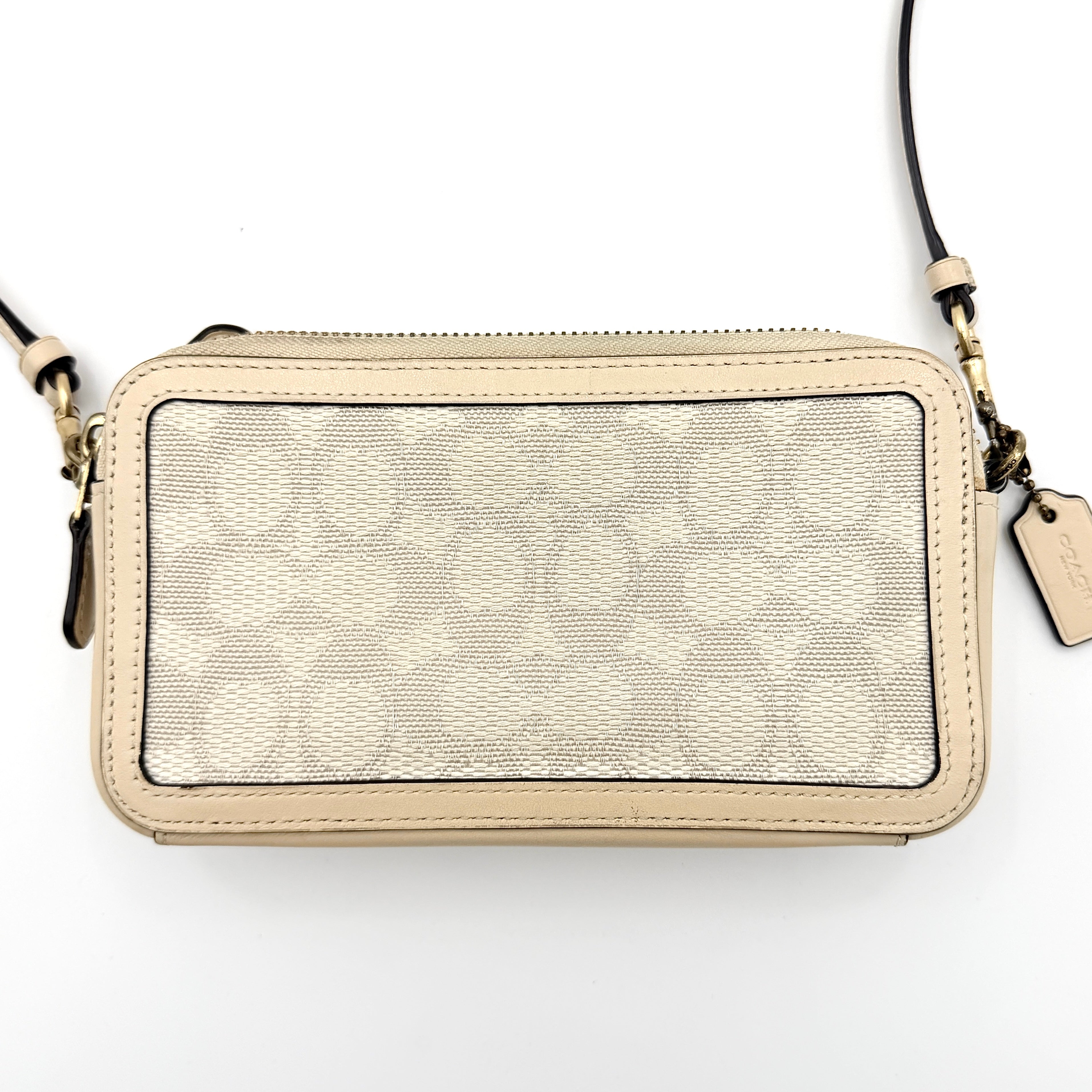 Coach Signature Kira Crossbody Bag in beige and white jacquard with leather trim and adjustable strap displayed against a white background.