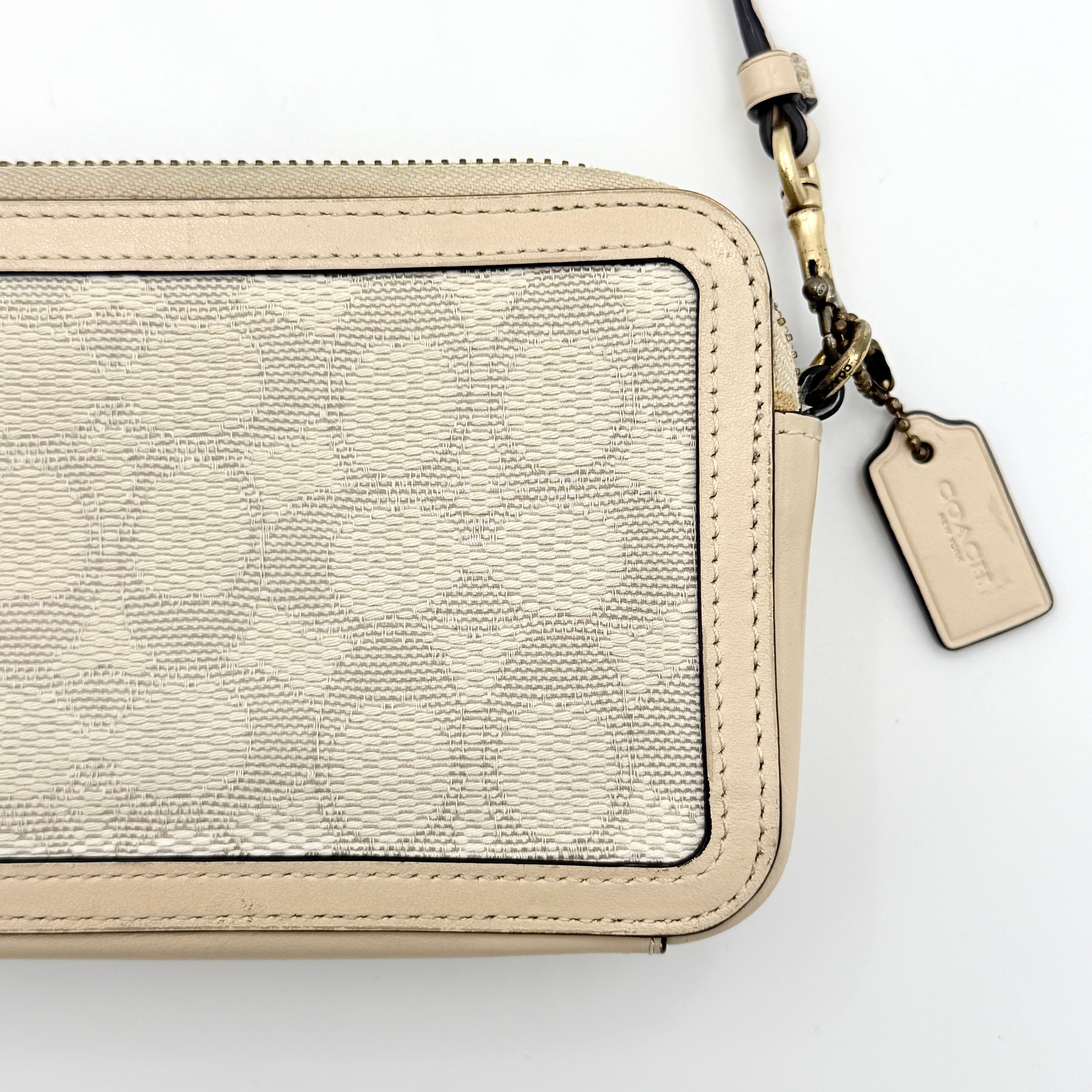 Coach Signature Kira Crossbody Bag in beige and white jacquard with leather trim and adjustable strap displayed against a white background.
