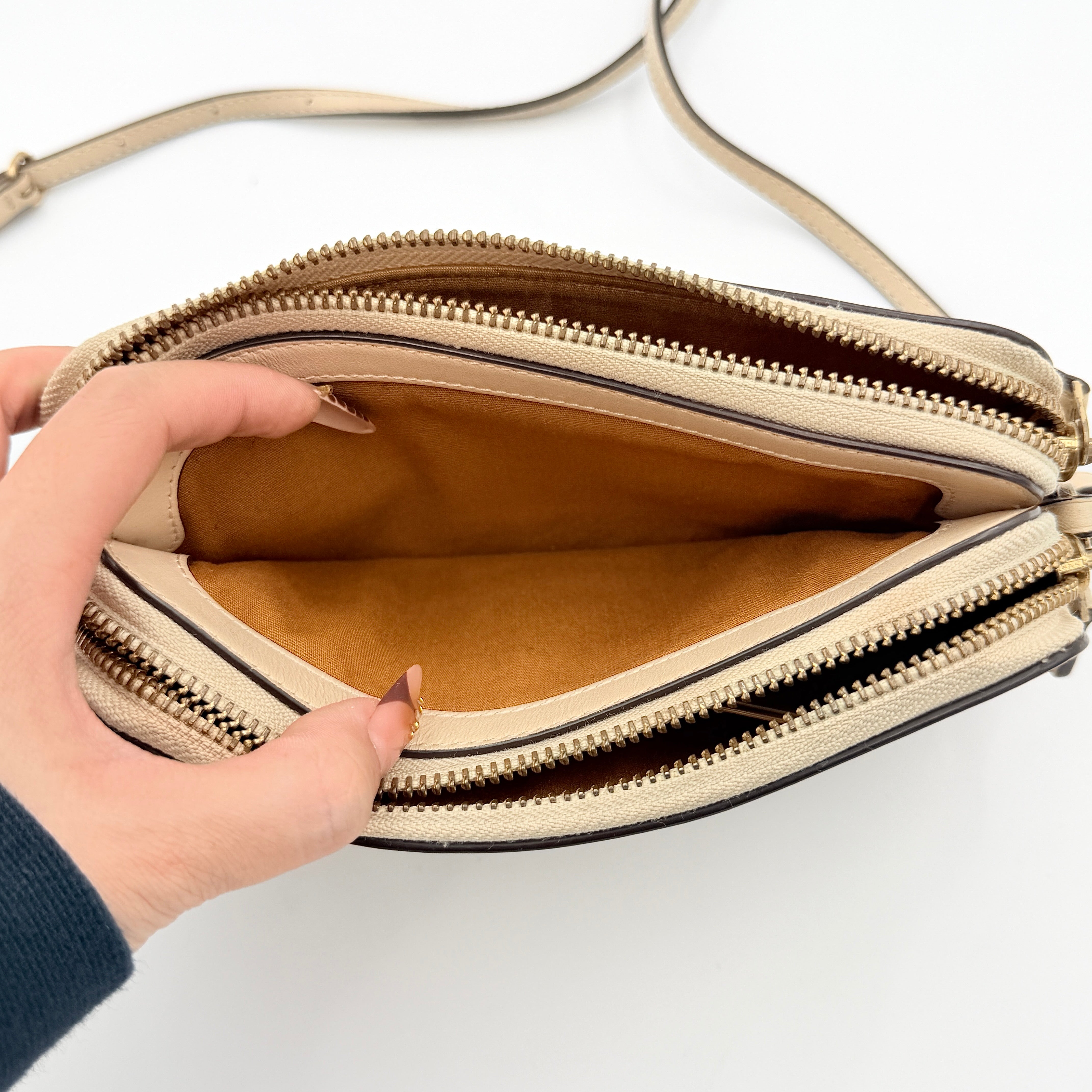 Coach Signature Kira Crossbody Bag in beige and white jacquard with leather trim and adjustable strap displayed against a white background.