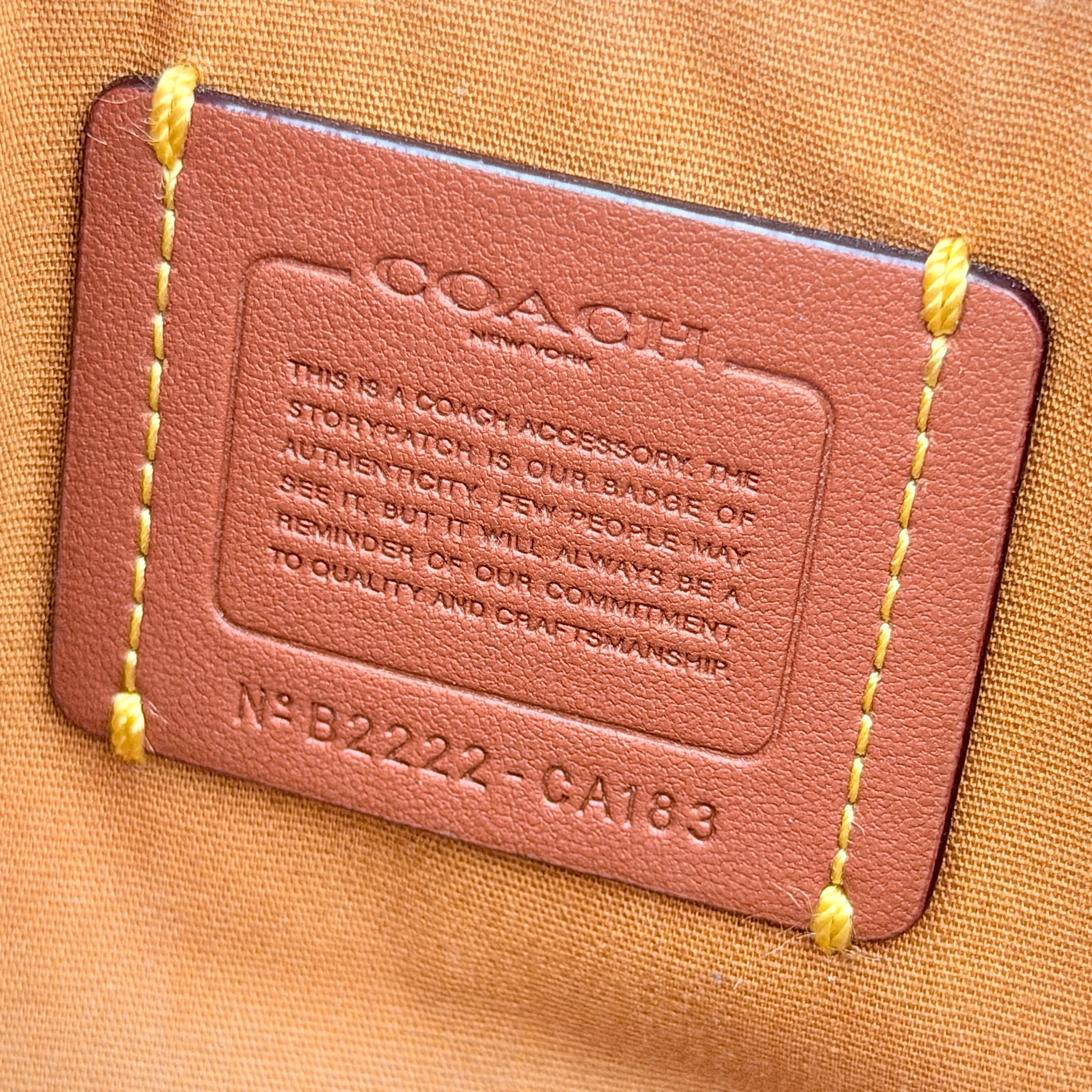 Coach Signature Kira Crossbody Bag in beige and white jacquard with leather trim and adjustable strap displayed against a white background.