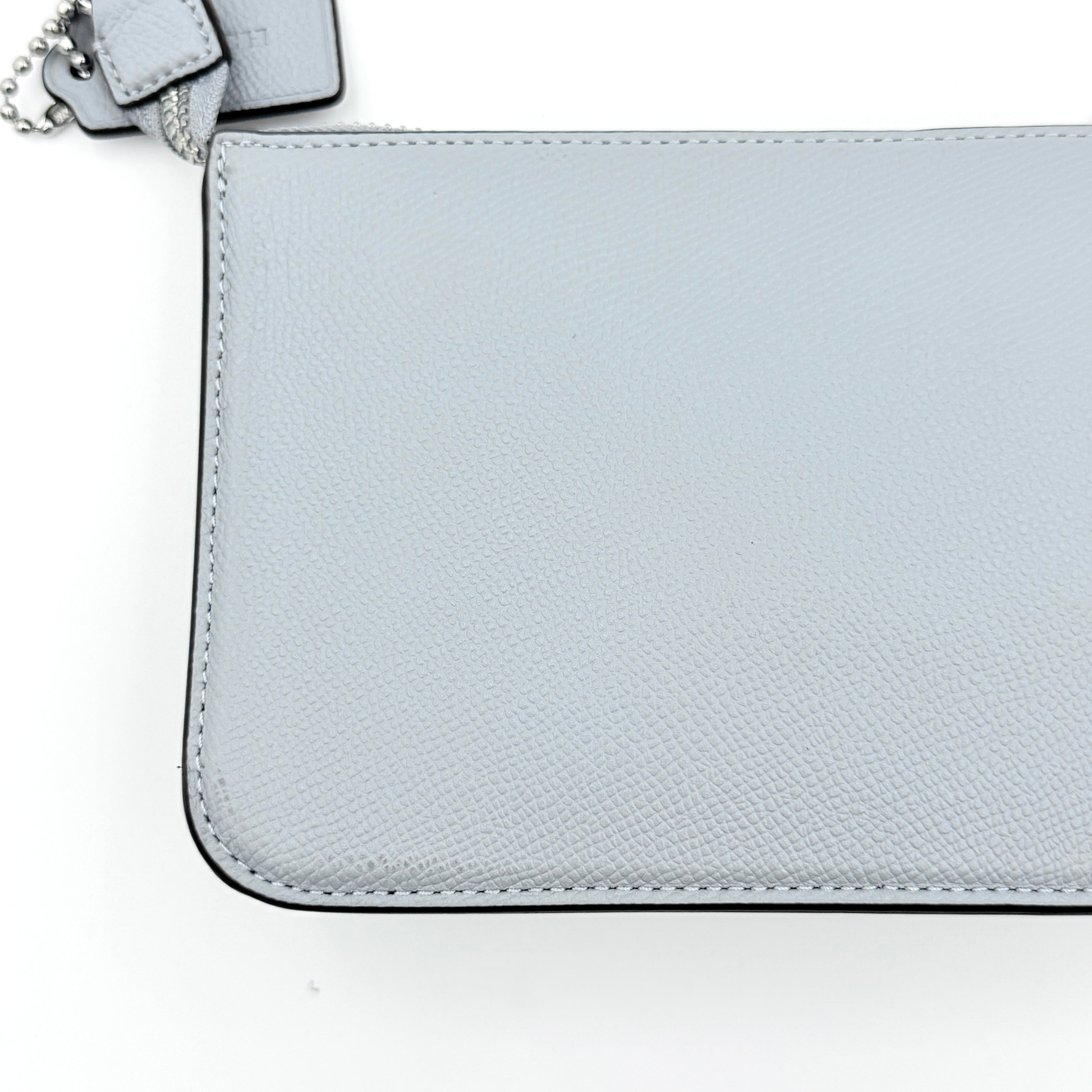Sky blue Coach grained leather shoulder bag with silver-tone C plaque and short strap, displayed against a white background.