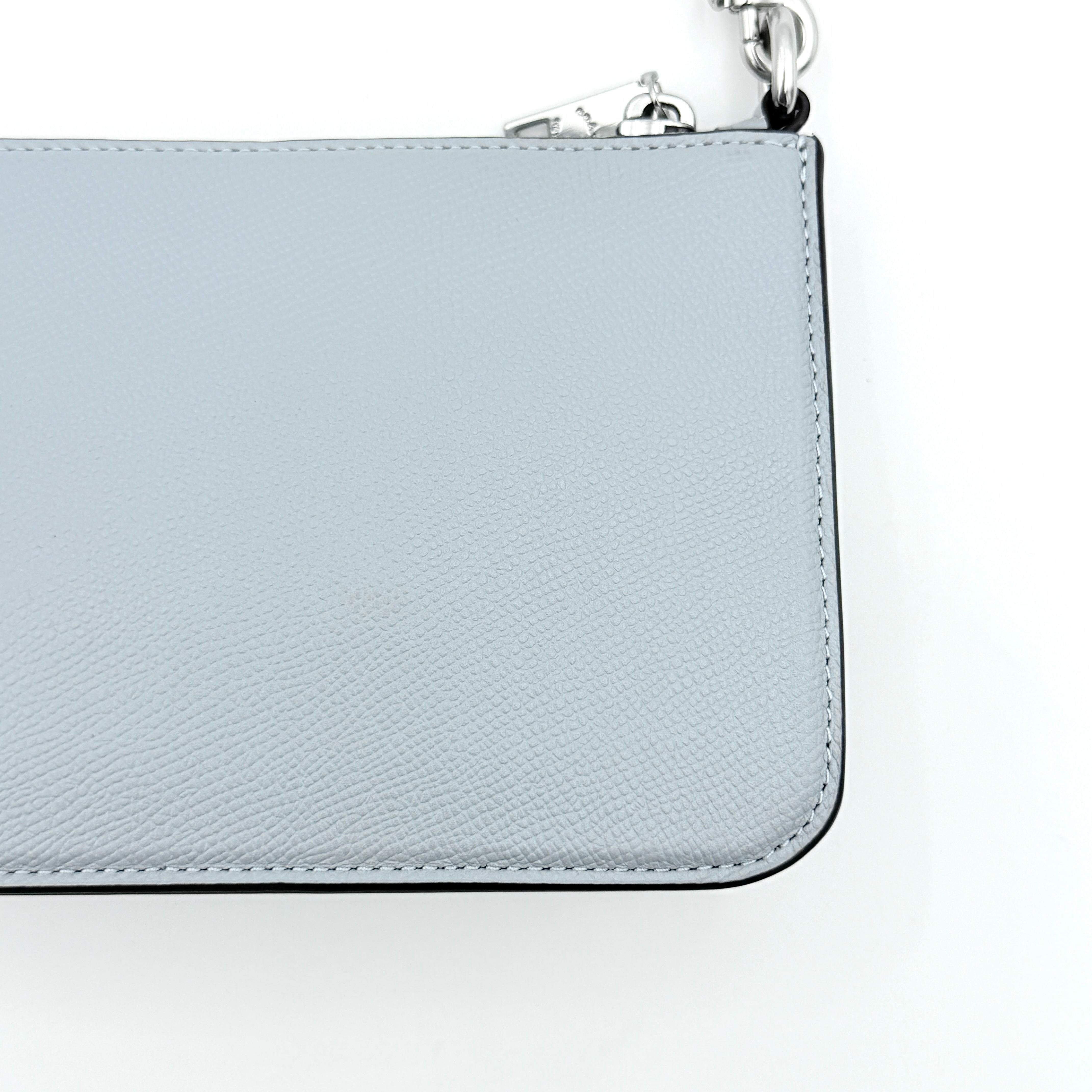 Sky blue Coach grained leather shoulder bag with silver-tone C plaque and short strap, displayed against a white background.