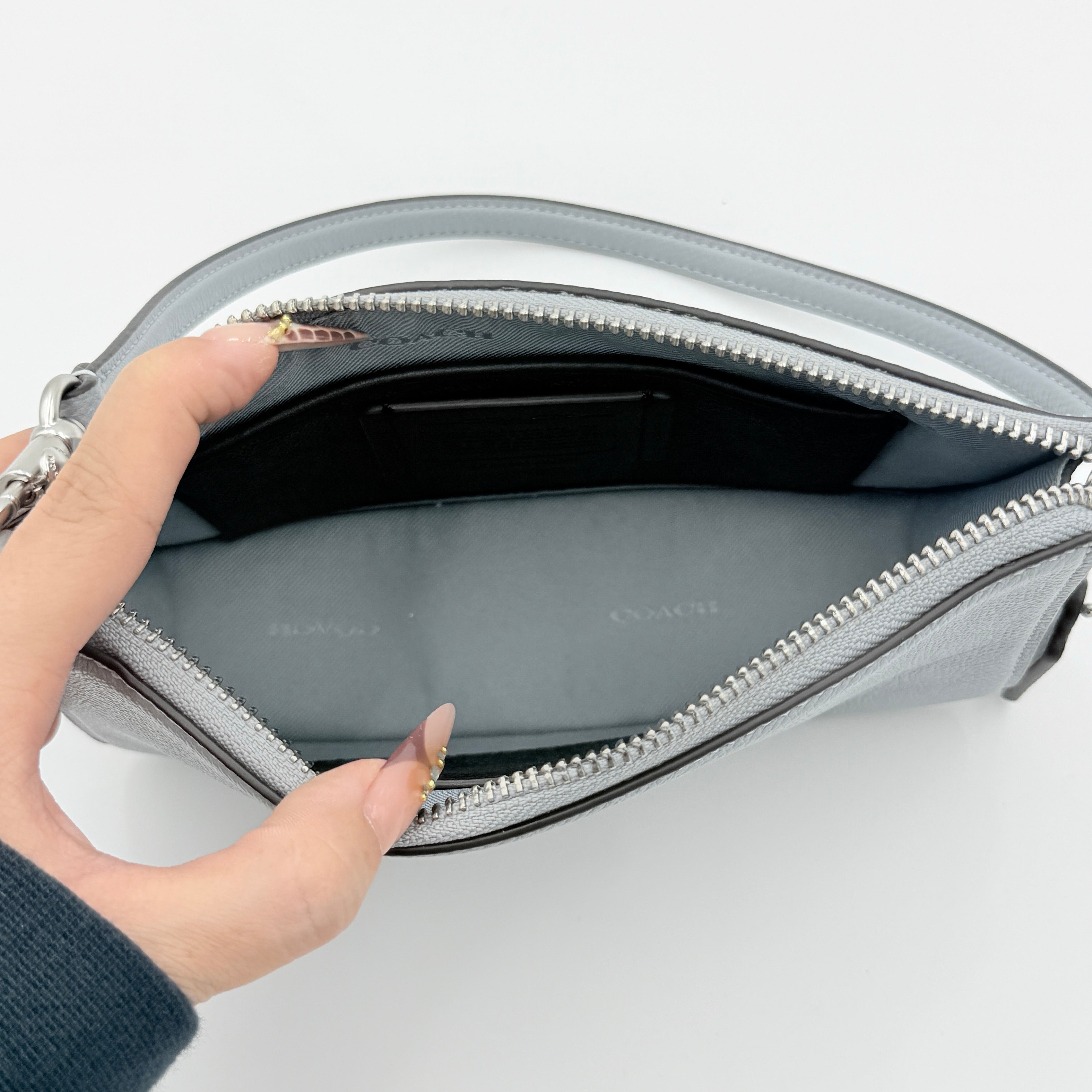 Sky blue Coach grained leather shoulder bag with silver-tone C plaque and short strap, displayed against a white background.
