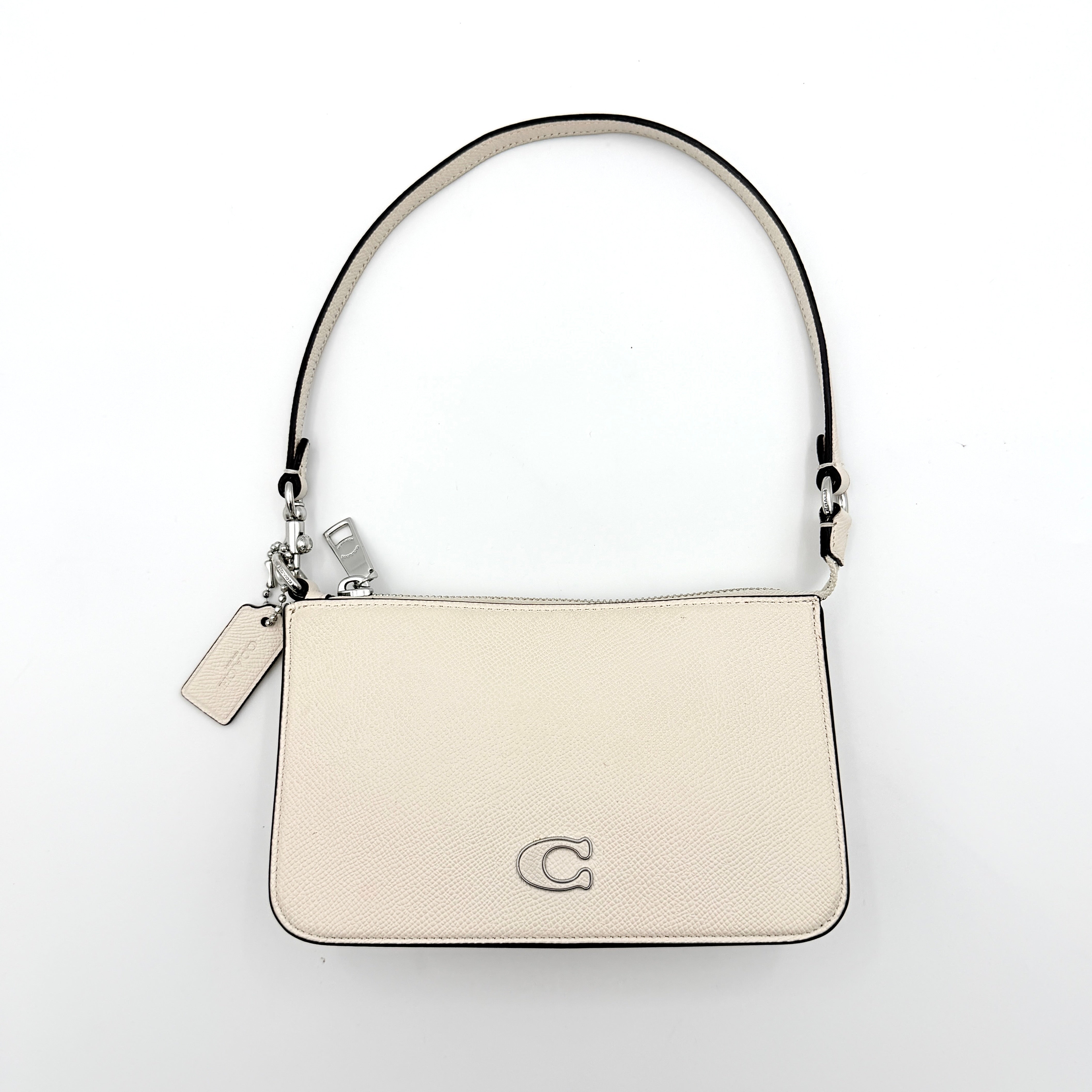 Coach cream grained leather shoulder bag with silver logo plaque and structured handle, displayed against a white background.