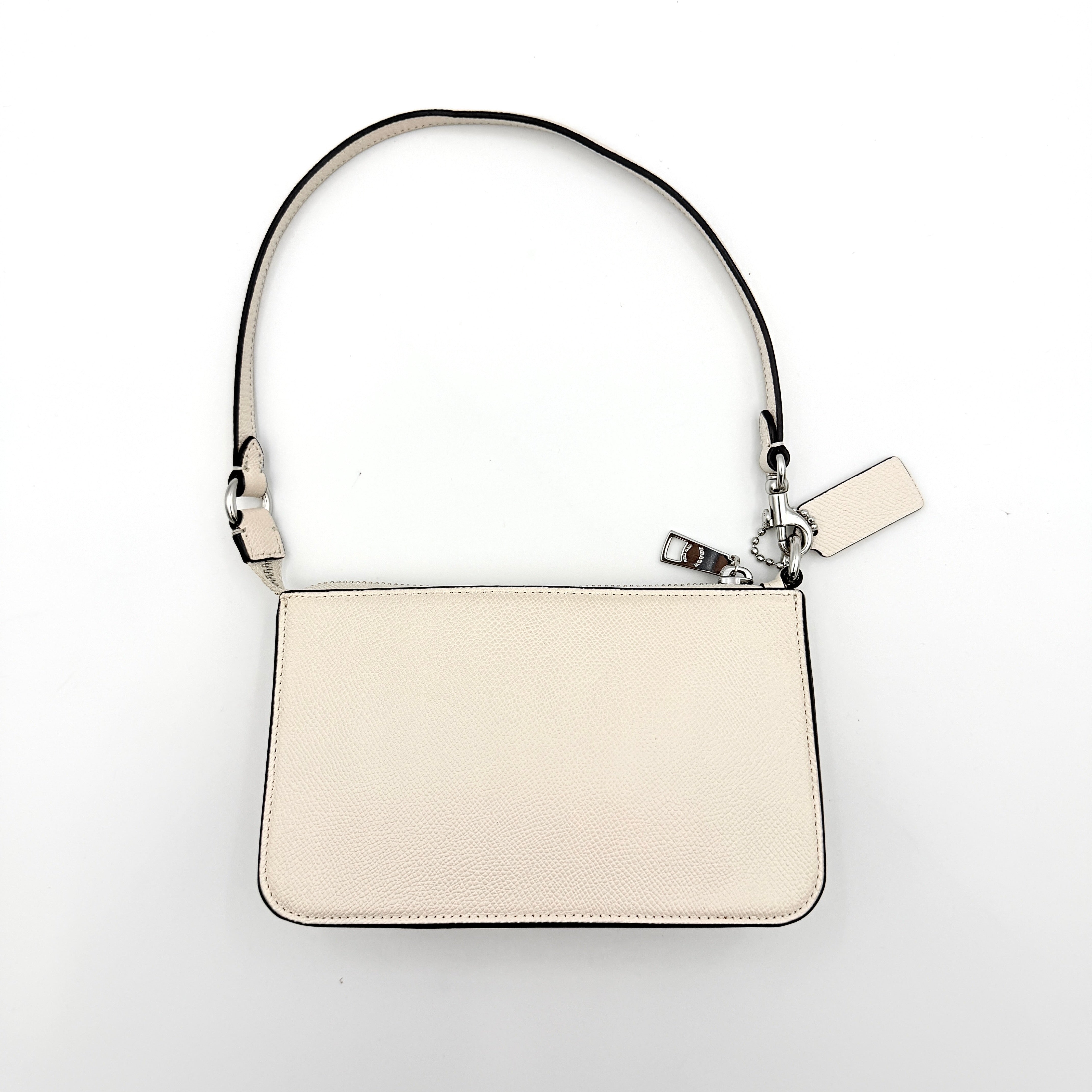 Coach cream grained leather shoulder bag with silver logo plaque and structured handle, displayed against a white background.