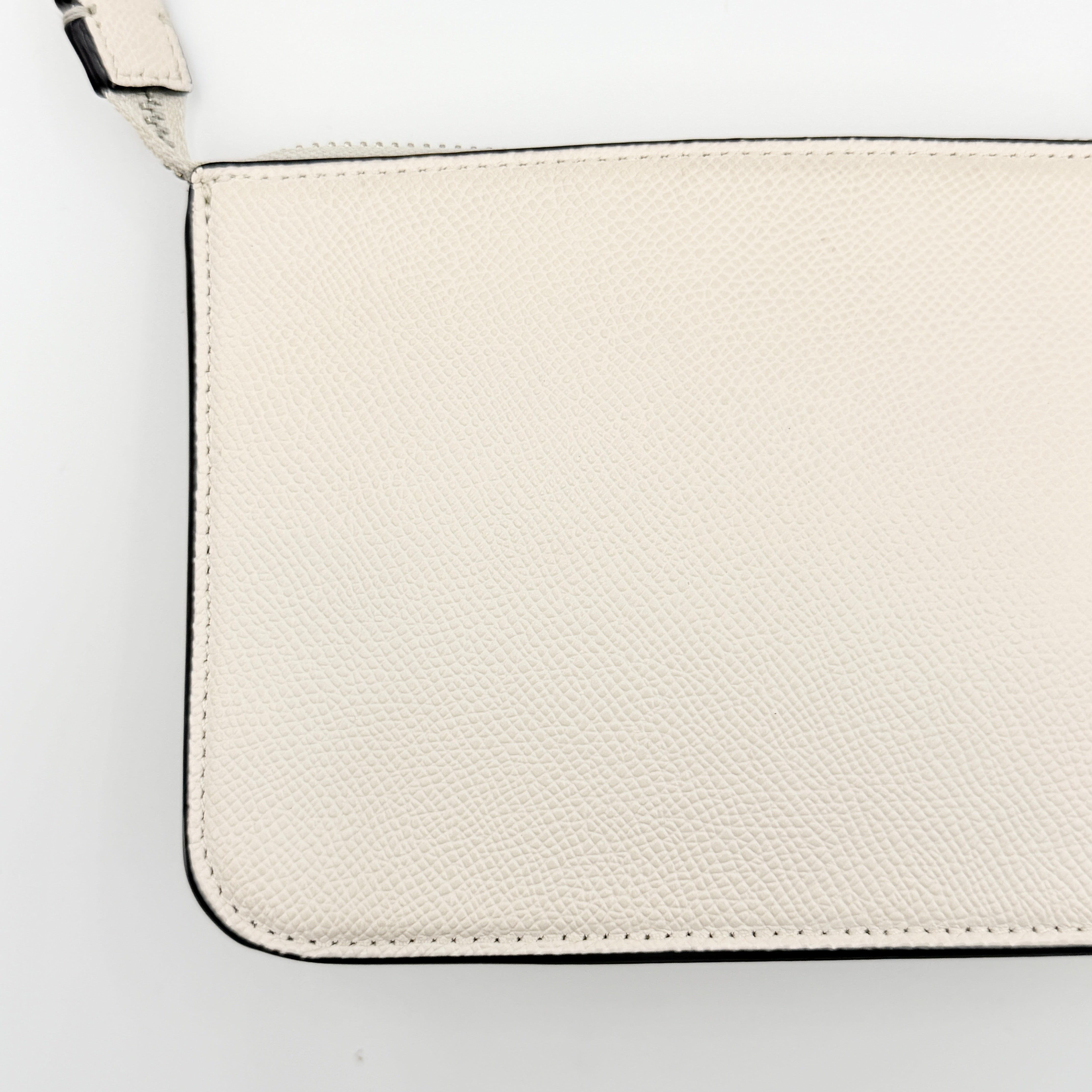 Coach cream grained leather shoulder bag with silver logo plaque and structured handle, displayed against a white background.