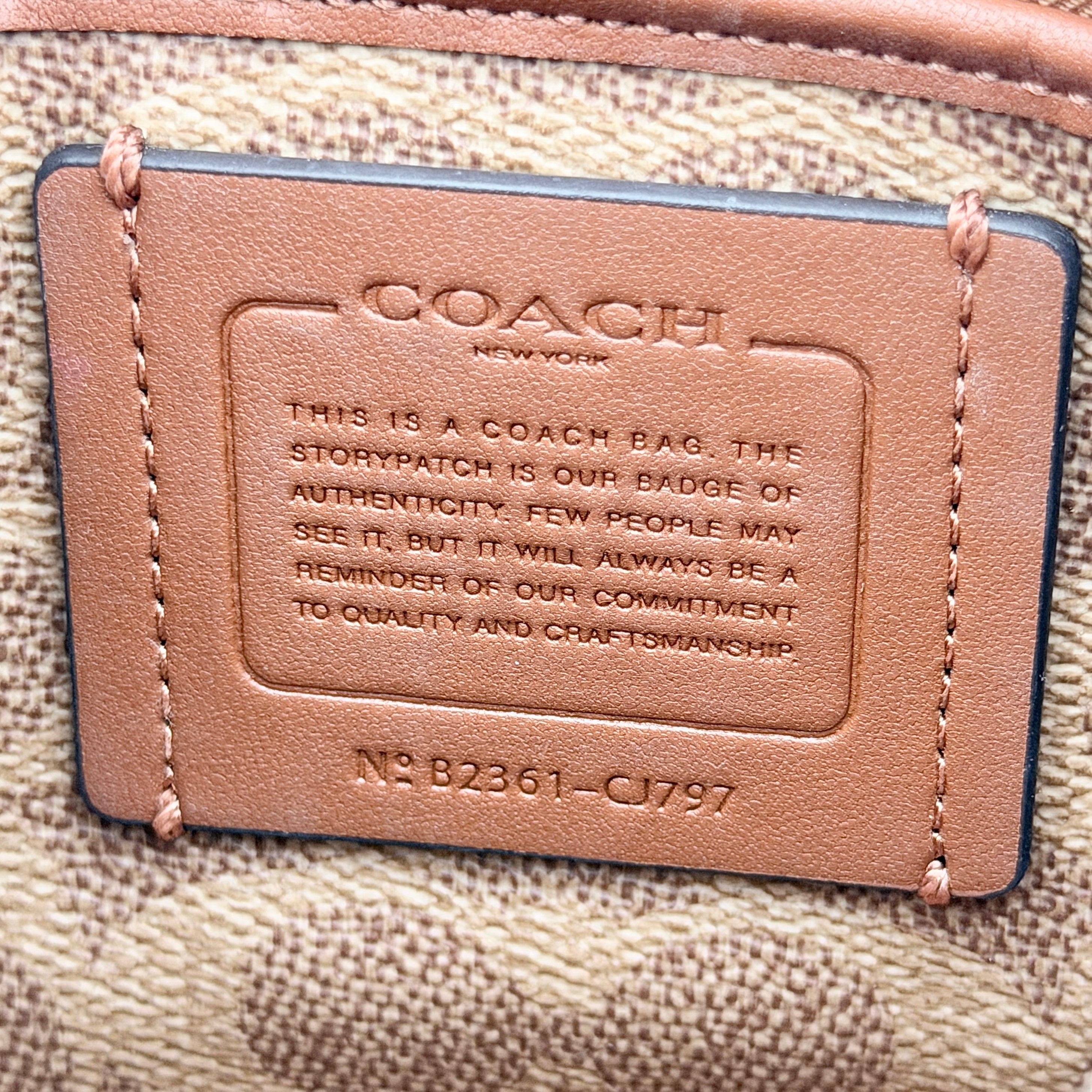 Coach cream grained leather shoulder bag with silver logo plaque and structured handle, displayed against a white background.