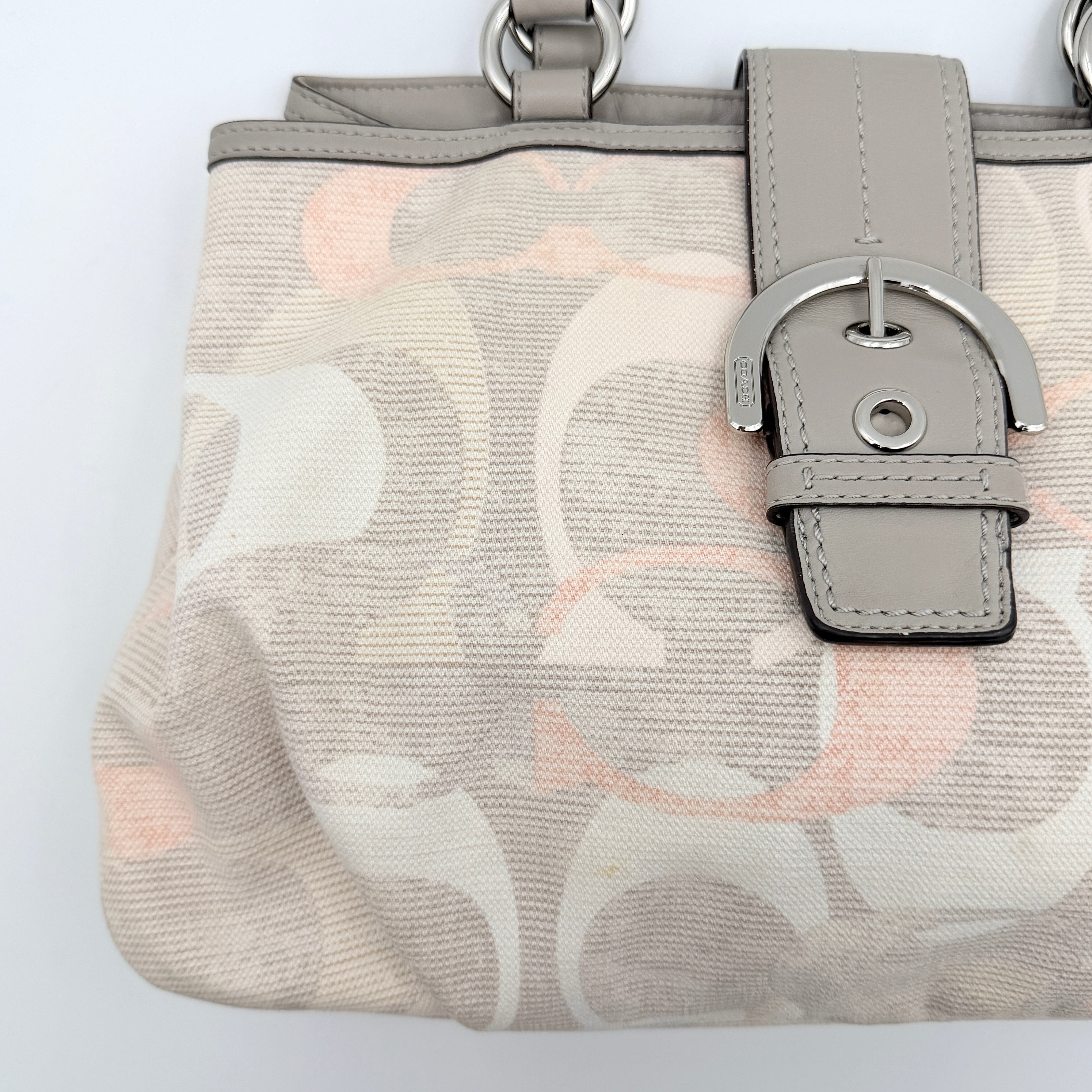 Coach Signature Optic Soho Shoulder Bag in grey and pink canvas with leather handles and buckle detail, shown against a white background.