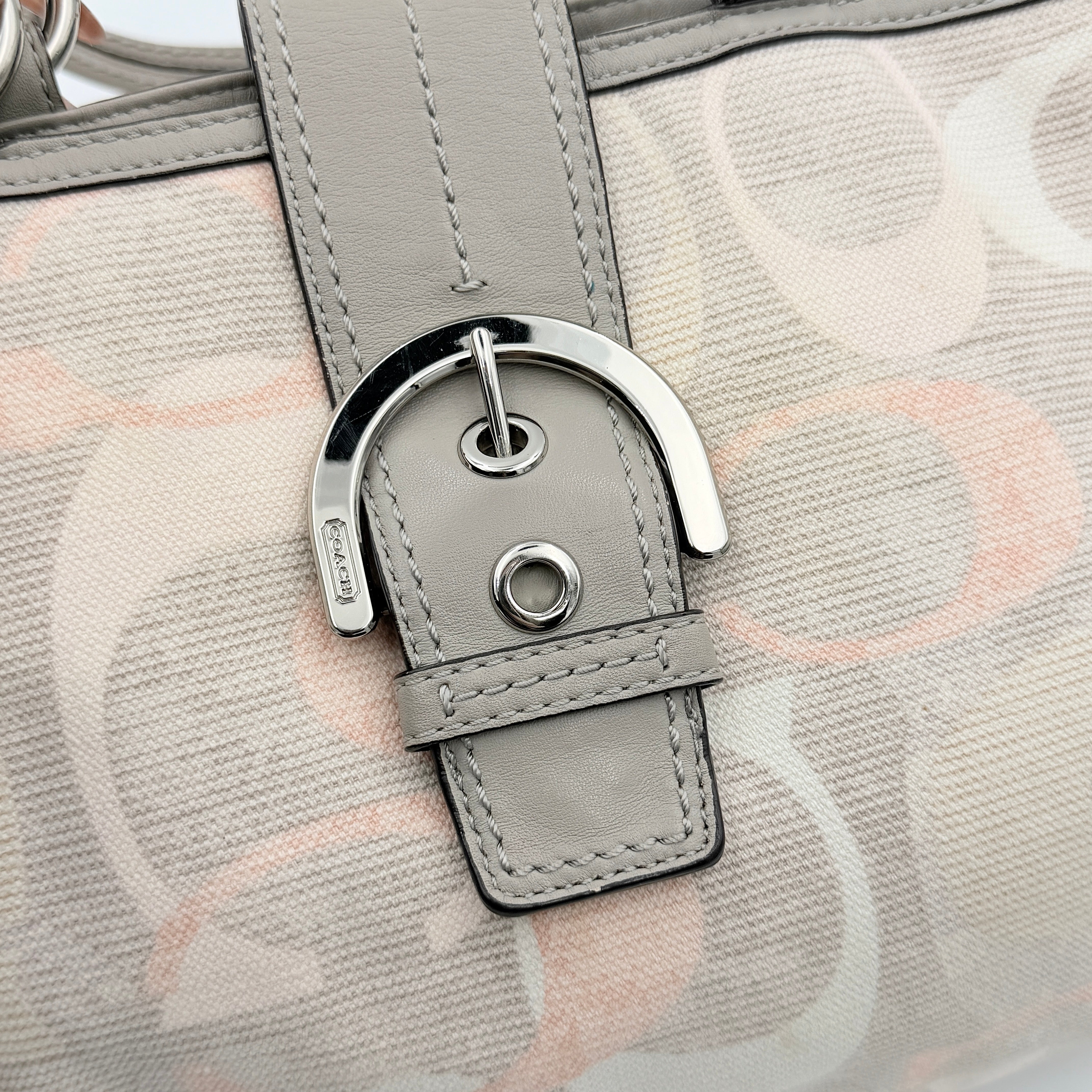 Coach Signature Optic Soho Shoulder Bag in grey and pink canvas with leather handles and buckle detail, shown against a white background.