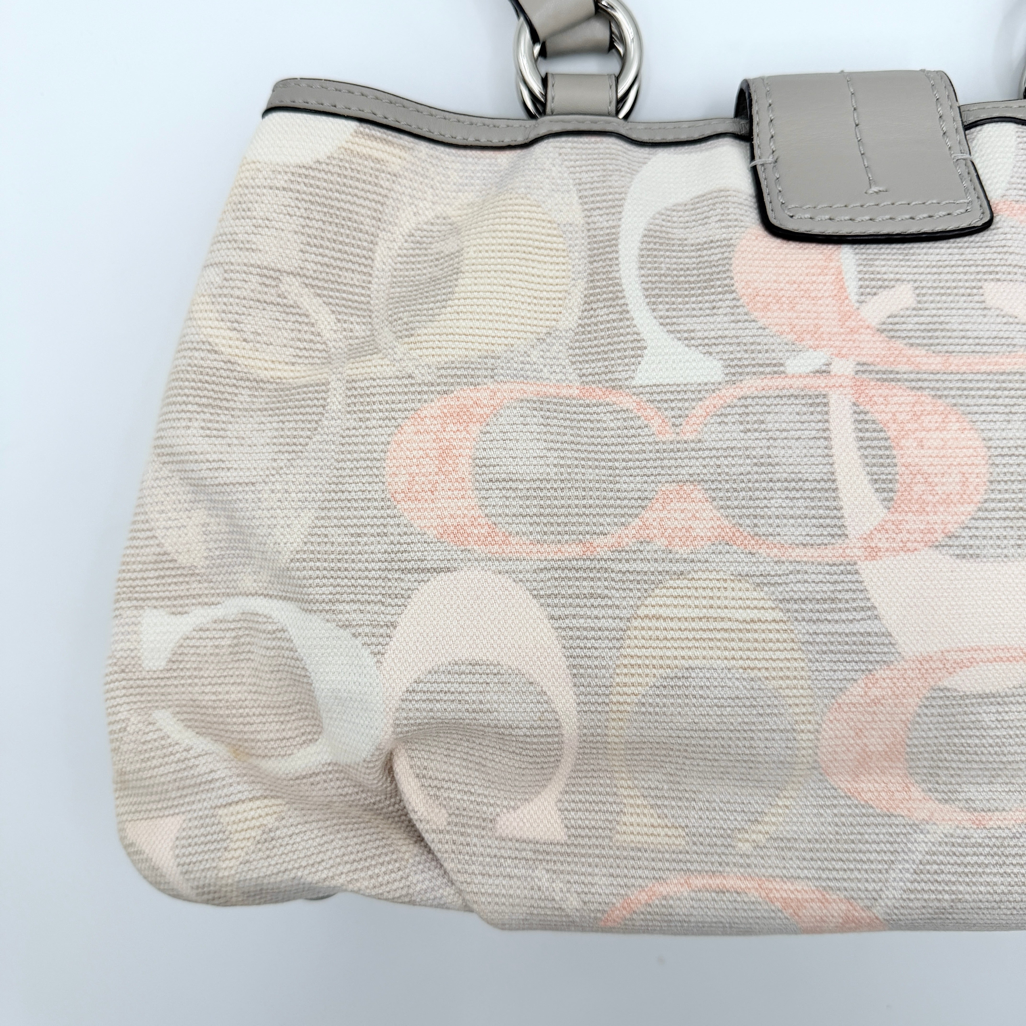 Coach Signature Optic Soho Shoulder Bag in grey and pink canvas with leather handles and buckle detail, shown against a white background.