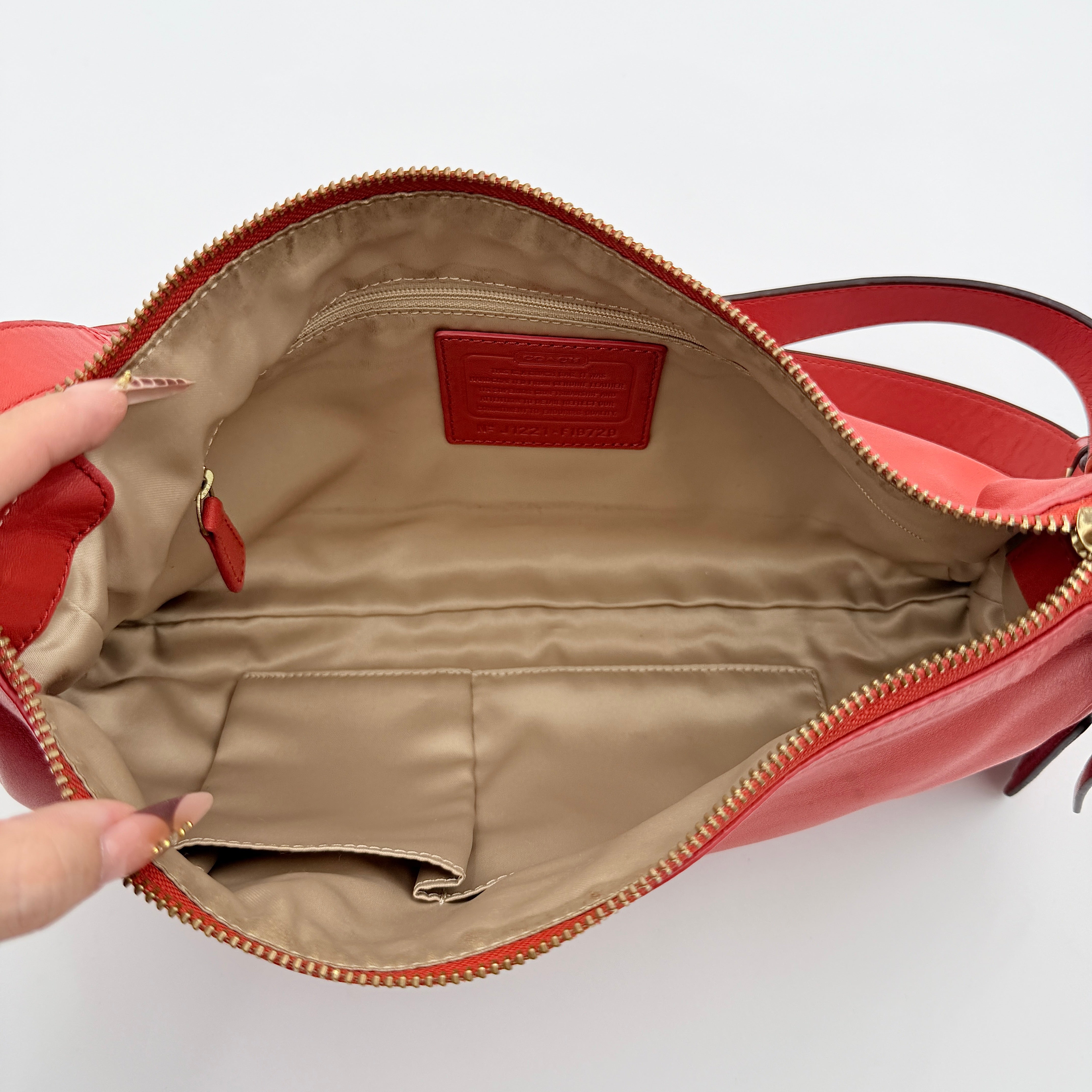 Coach 2Way Park Shoulder Bag in orange leather with gold hardware and adjustable strap, displayed against a white background.