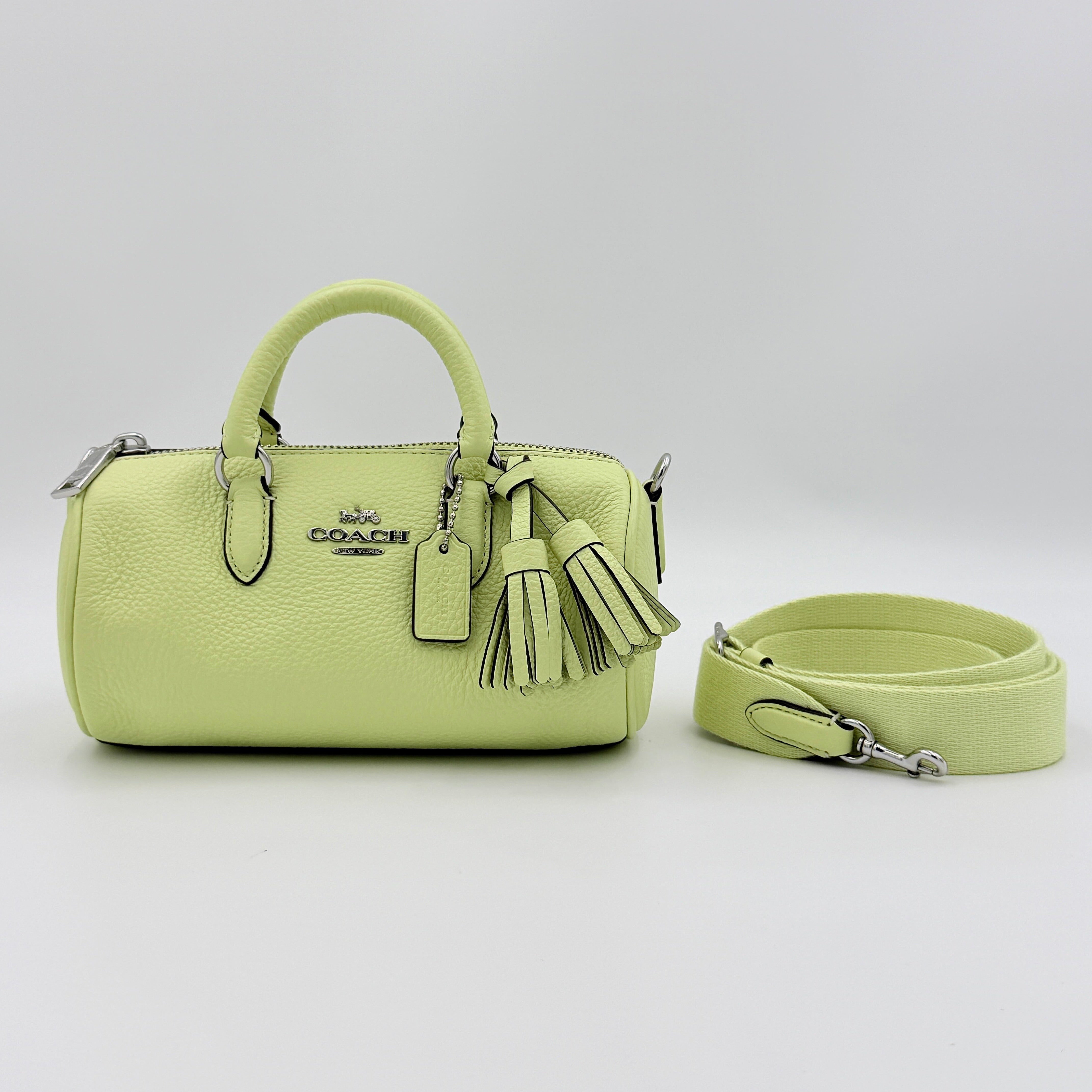 Coach 2Way Lacey Mini Boston Bag in light green pebbled leather with tassels and a detachable strap, shown against a plain background.