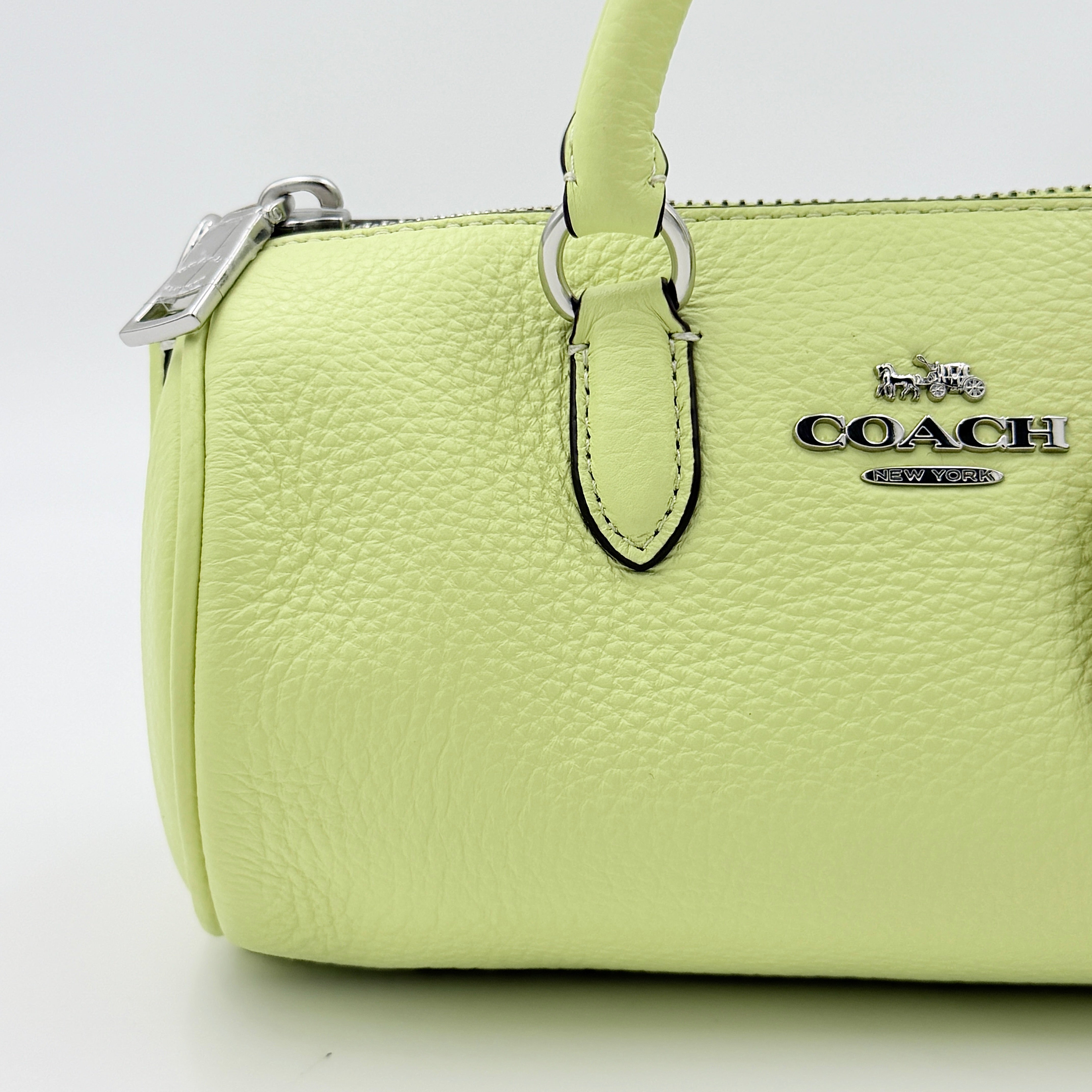 Coach 2Way Lacey Mini Boston Bag in light green pebbled leather with tassels and a detachable strap, shown against a plain background.