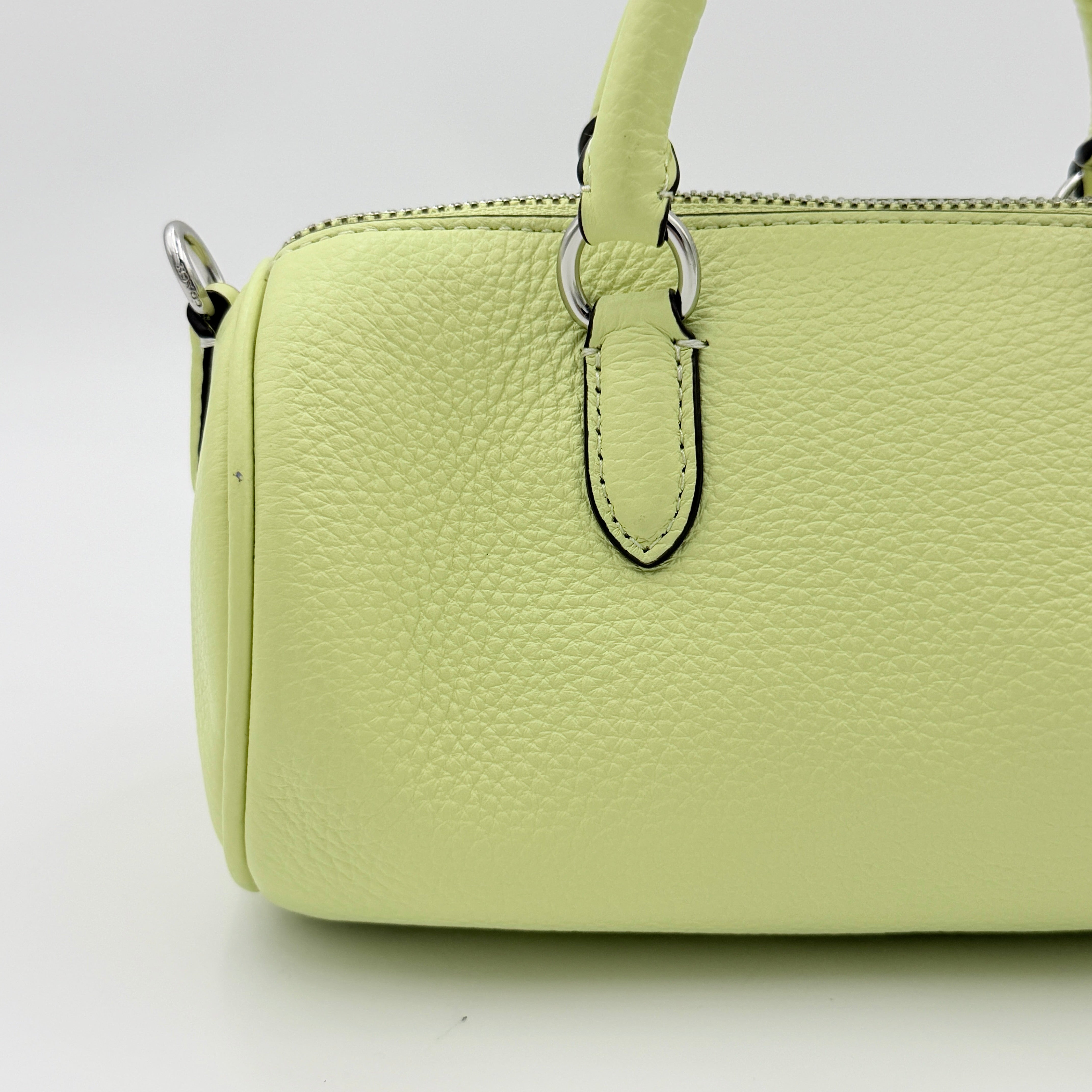 Coach 2Way Lacey Mini Boston Bag in light green pebbled leather with tassels and a detachable strap, shown against a plain background.