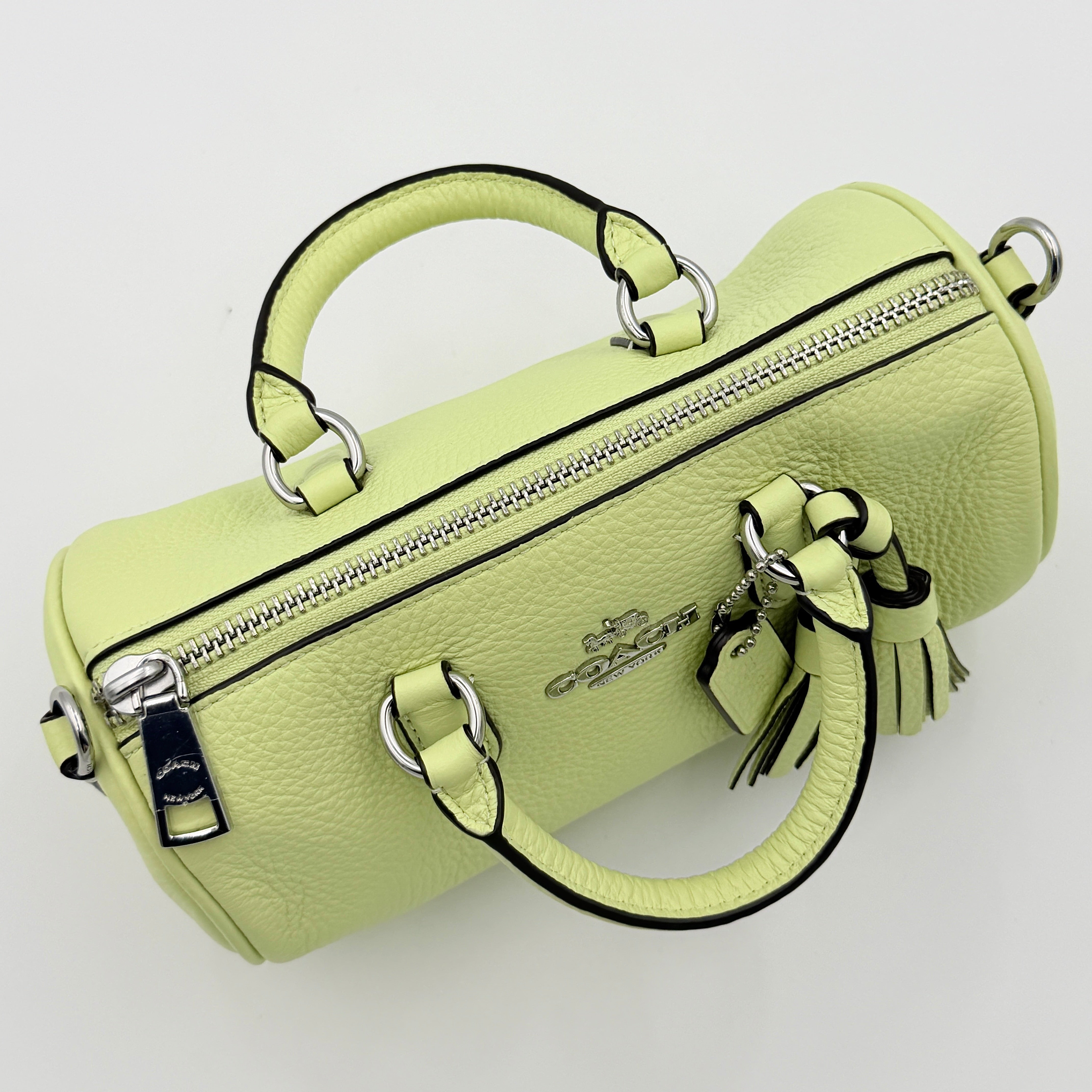 Coach 2Way Lacey Mini Boston Bag in light green pebbled leather with tassels and a detachable strap, shown against a plain background.