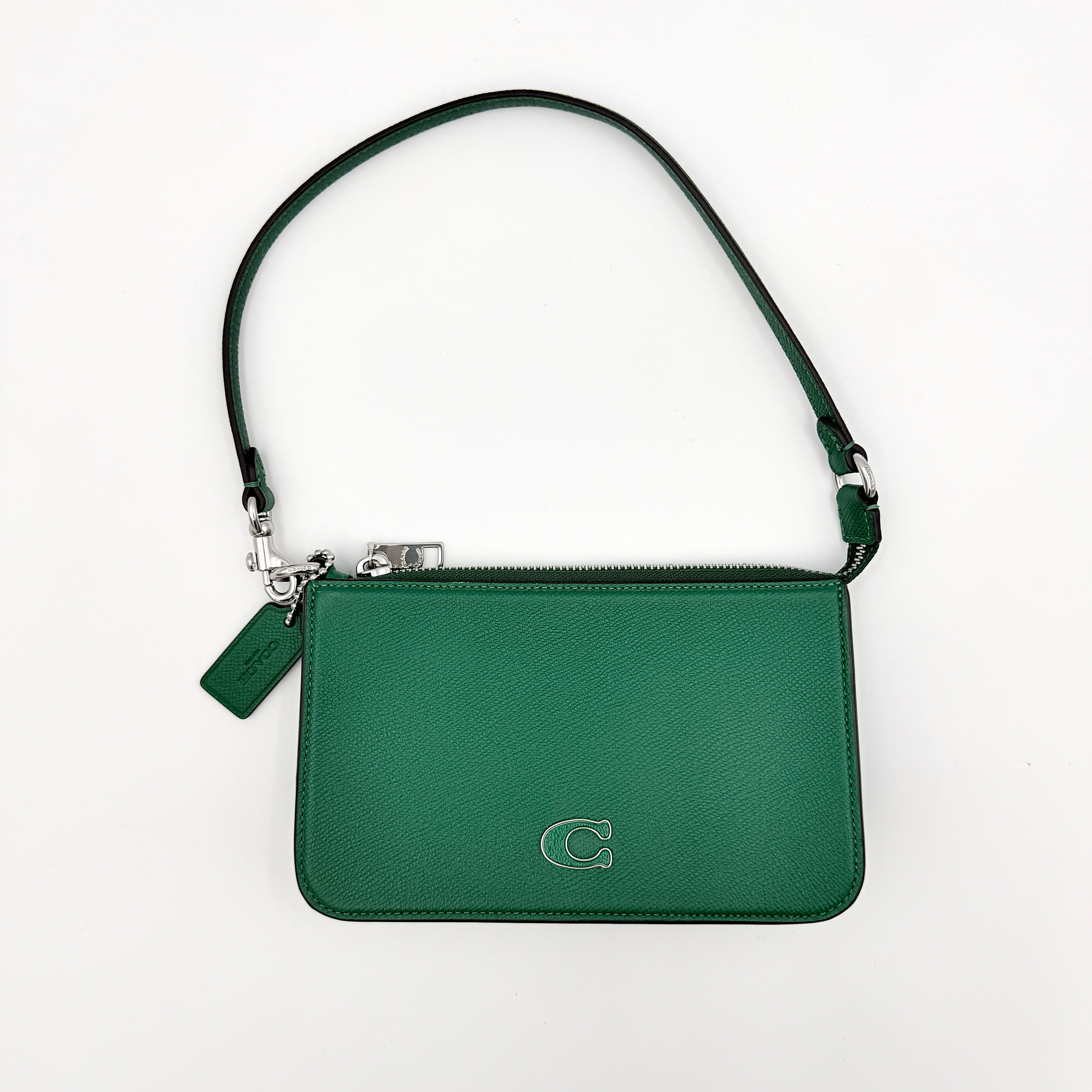 Coach green grained leather shoulder bag with silver C plaque and top zip, styled with a short strap.