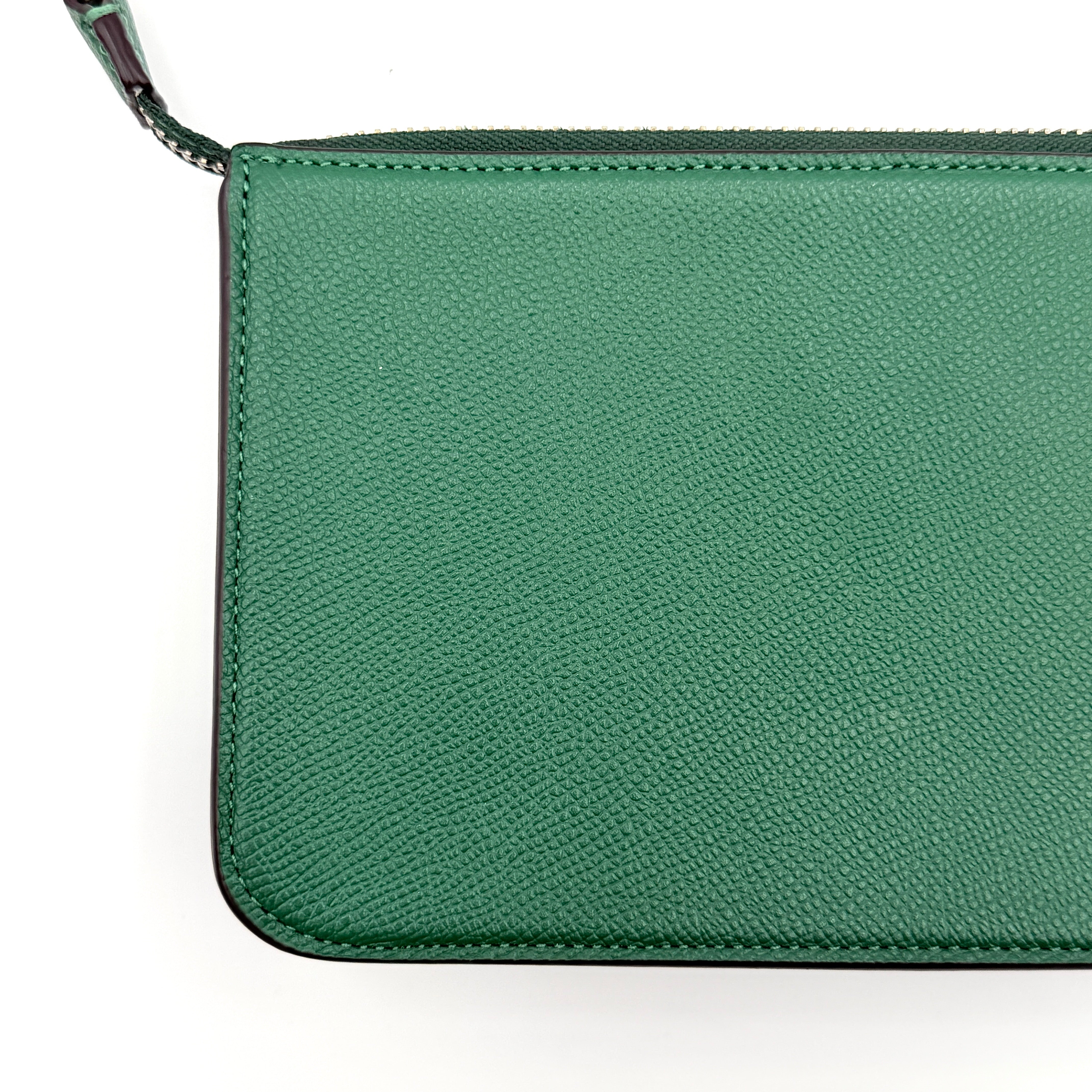 Coach green grained leather shoulder bag with silver C plaque and top zip, styled with a short strap.