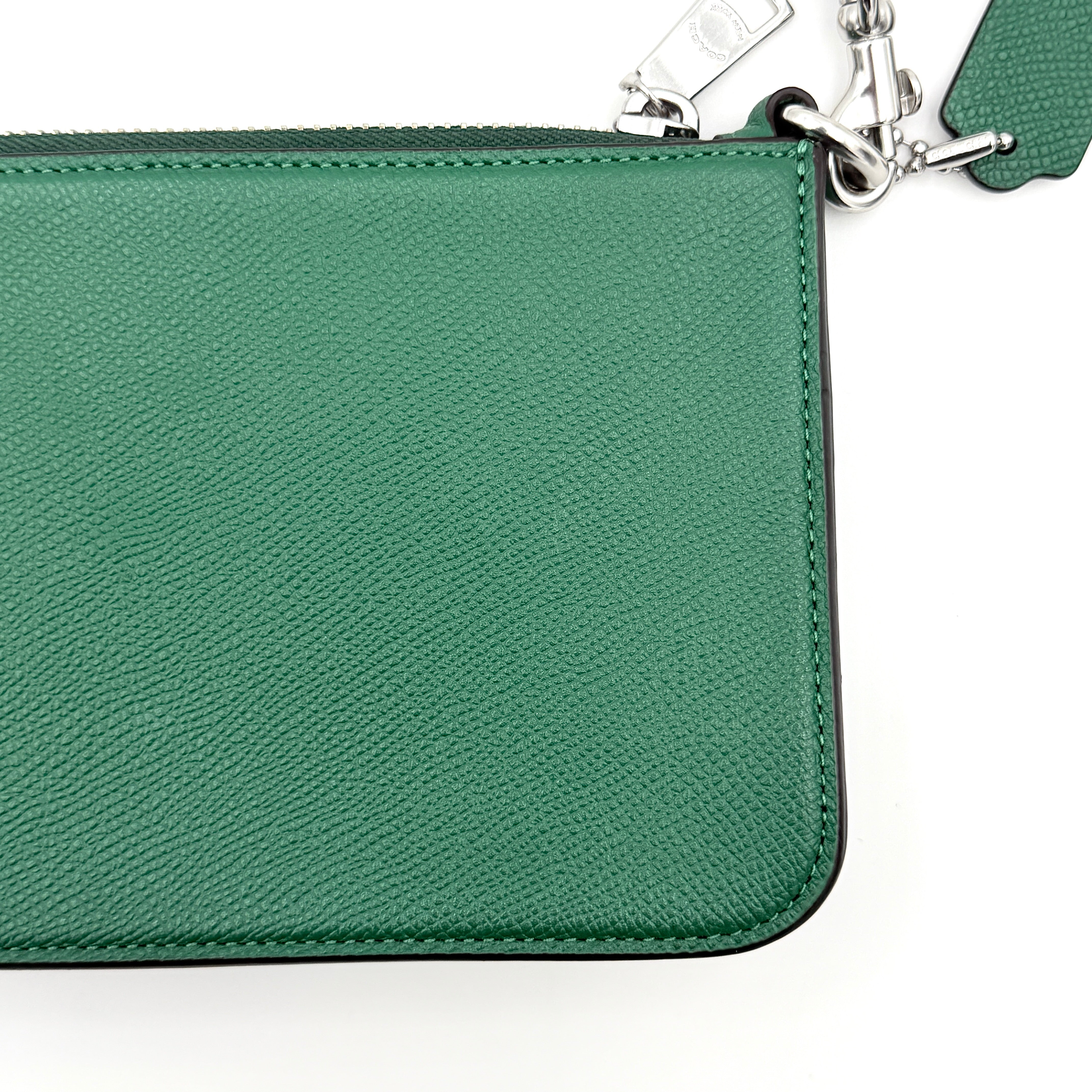 Coach green grained leather shoulder bag with silver C plaque and top zip, styled with a short strap.