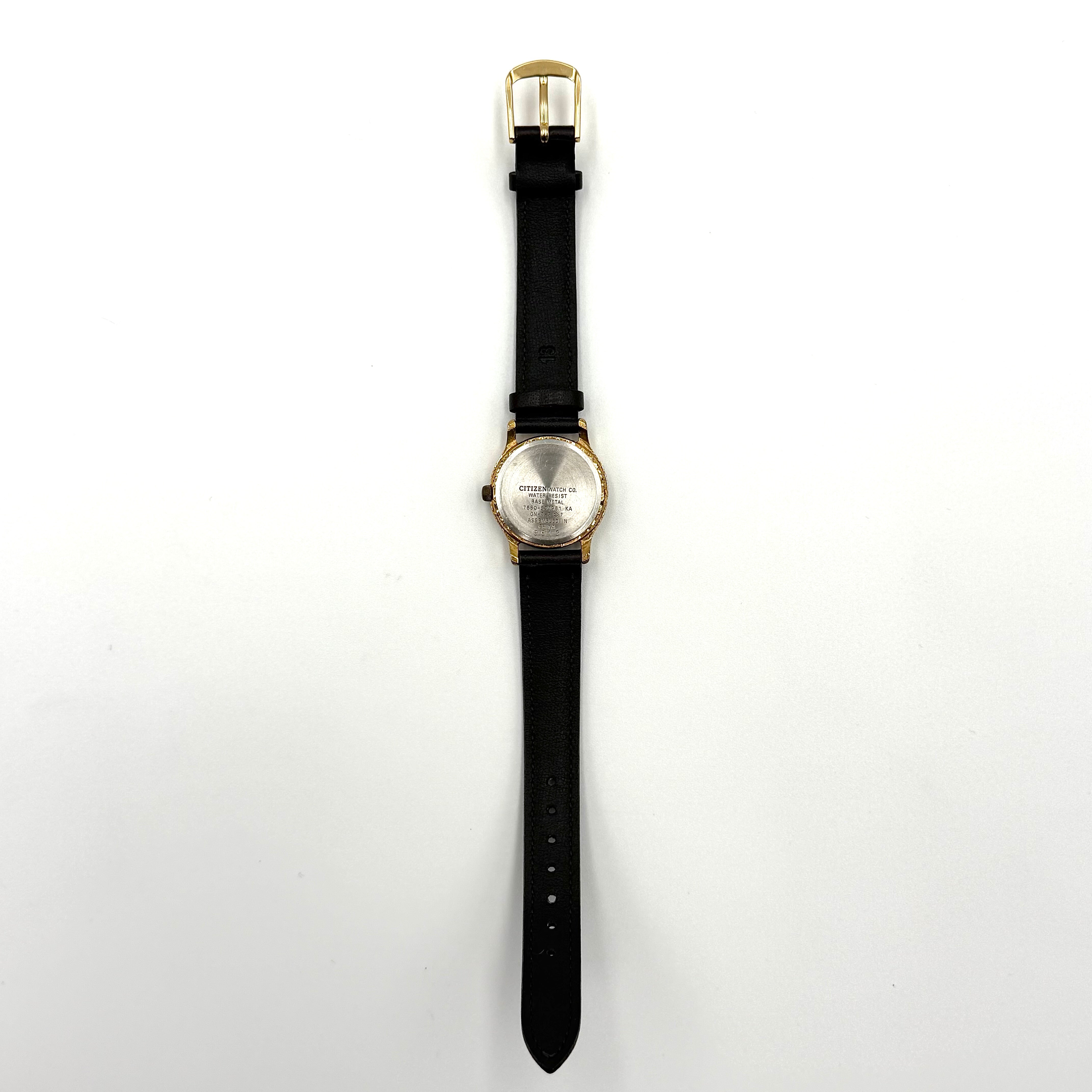 Citizen Freeway gold-tone quartz watch with black leather strap on a textured cushion