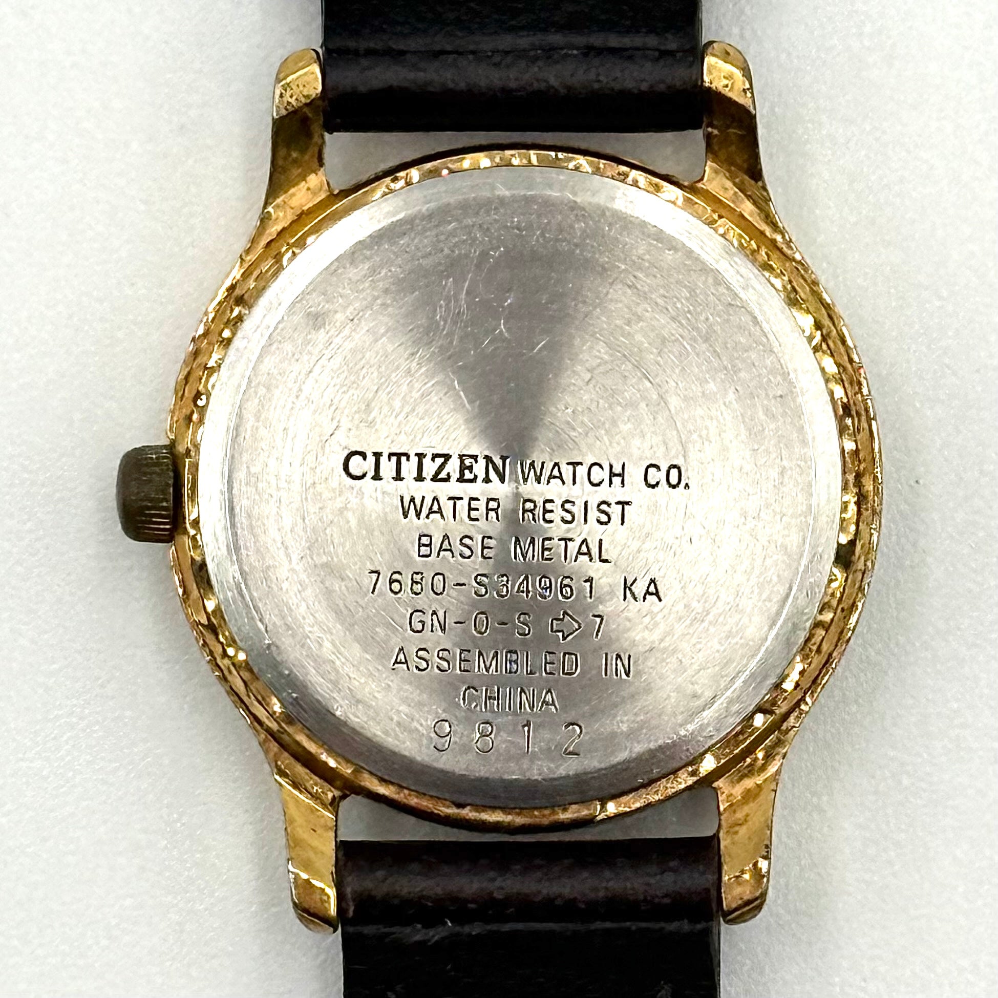 Citizen Freeway gold-tone quartz watch with black leather strap on a textured cushion