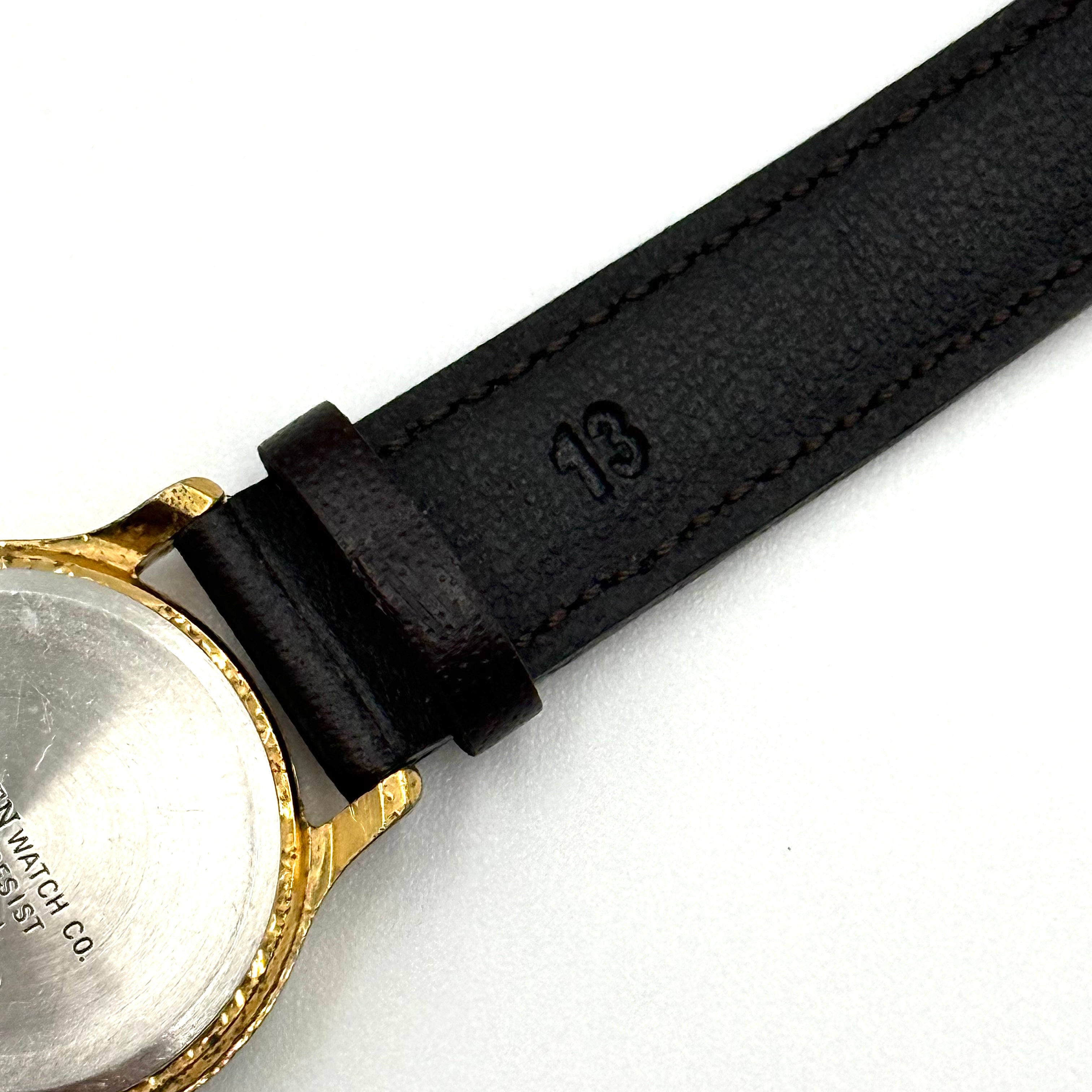Citizen Freeway gold-tone quartz watch with black leather strap on a textured cushion