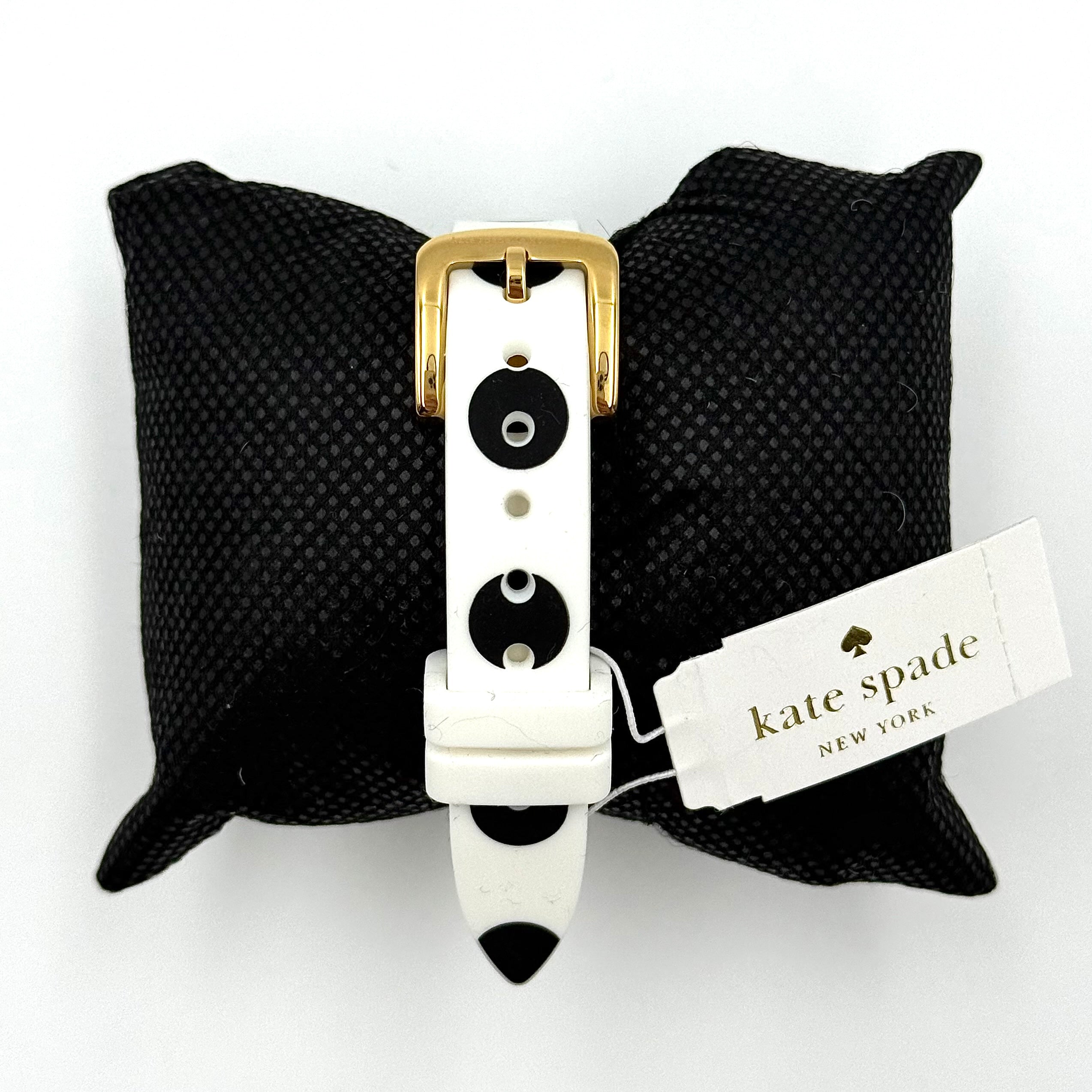 Kate Spade New York Rumsey 0838 silicone watch in white with black polka dots, gold-tone bezel, and white dial displayed on a cushion.