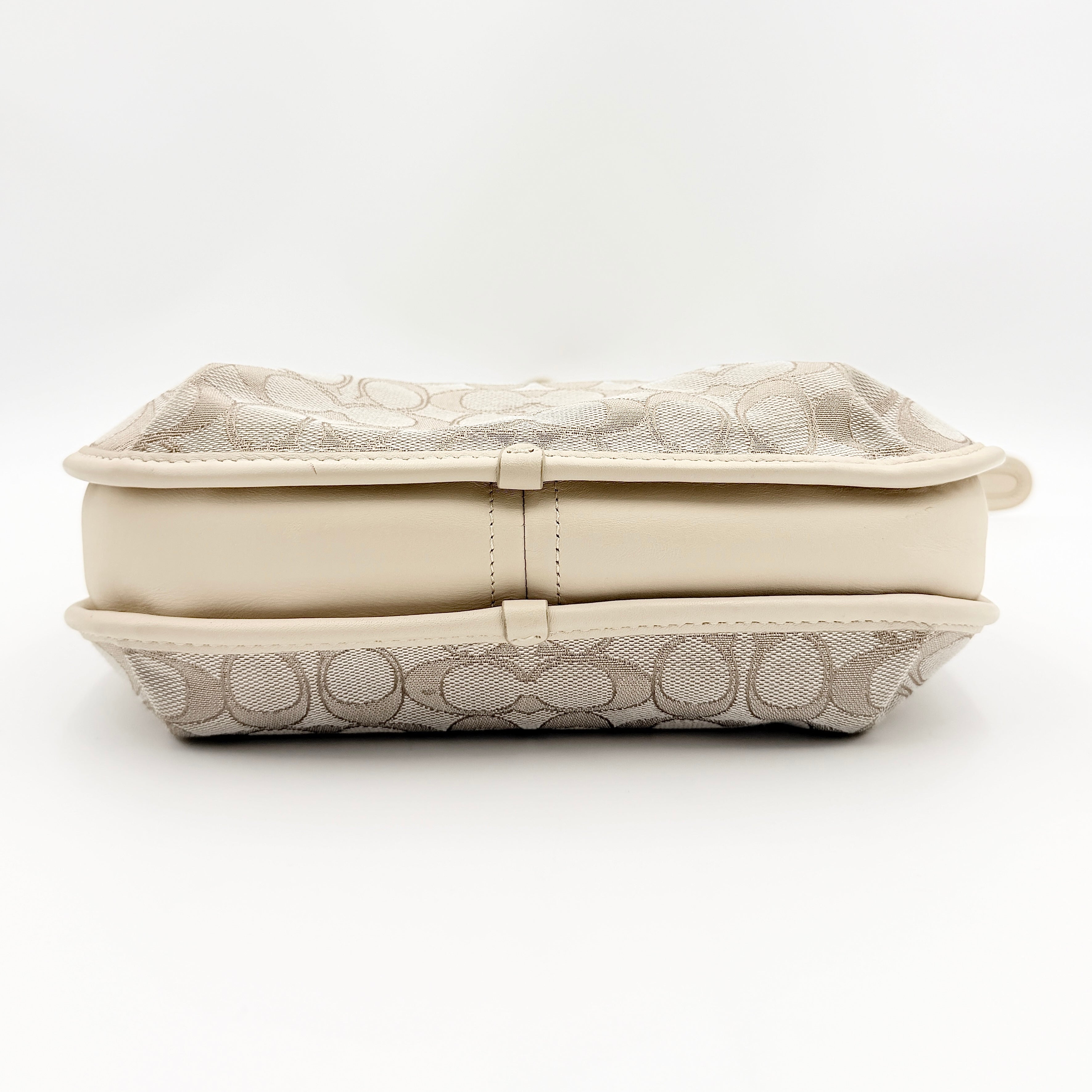 Coach Signature Ergo Shoulder Bag in beige and cream canvas with cream leather trim and brass adjustable buckle, displayed on a white background.