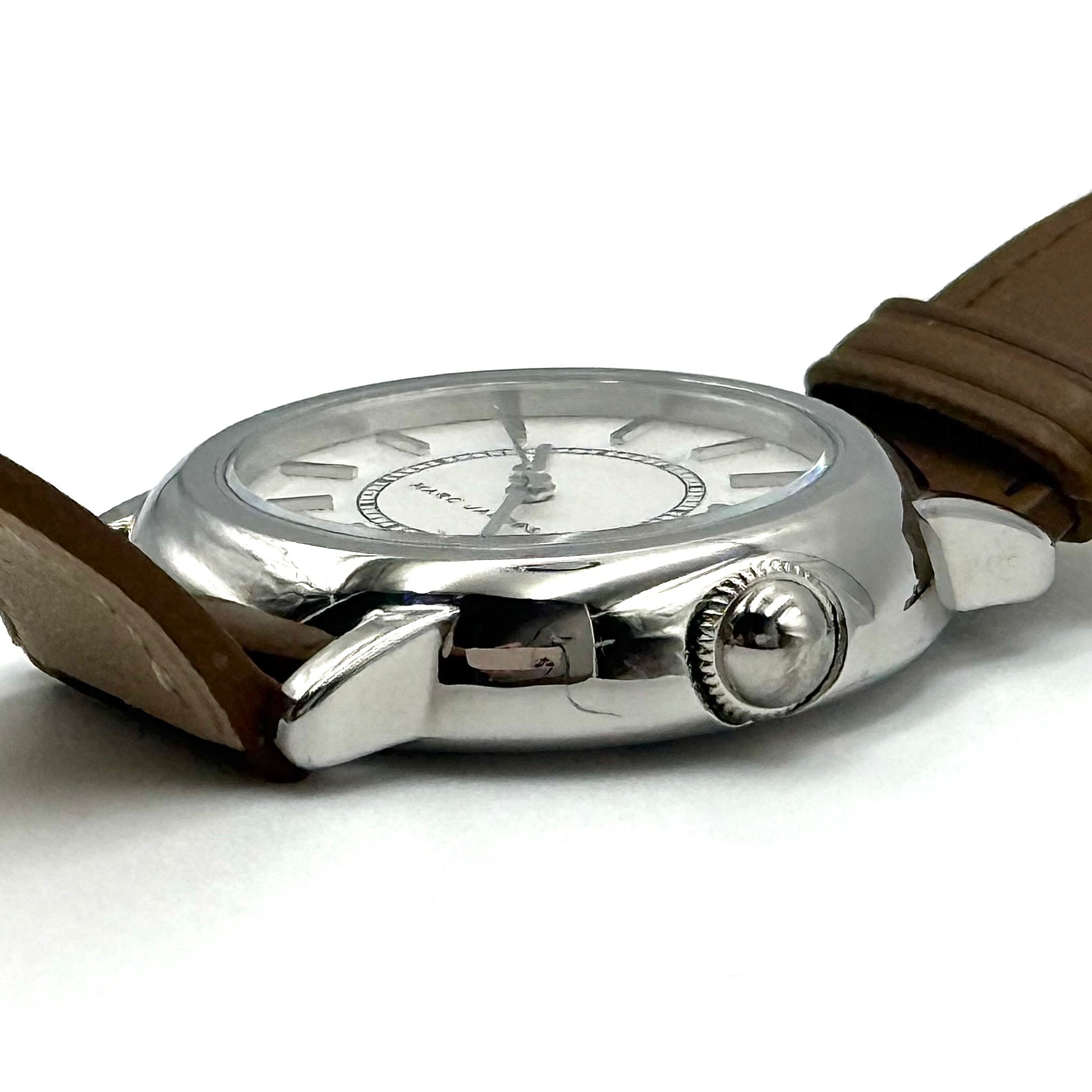 Marc Jacobs Courtney watch with silver stainless steel case and brown leather strap shown on a black cushion.