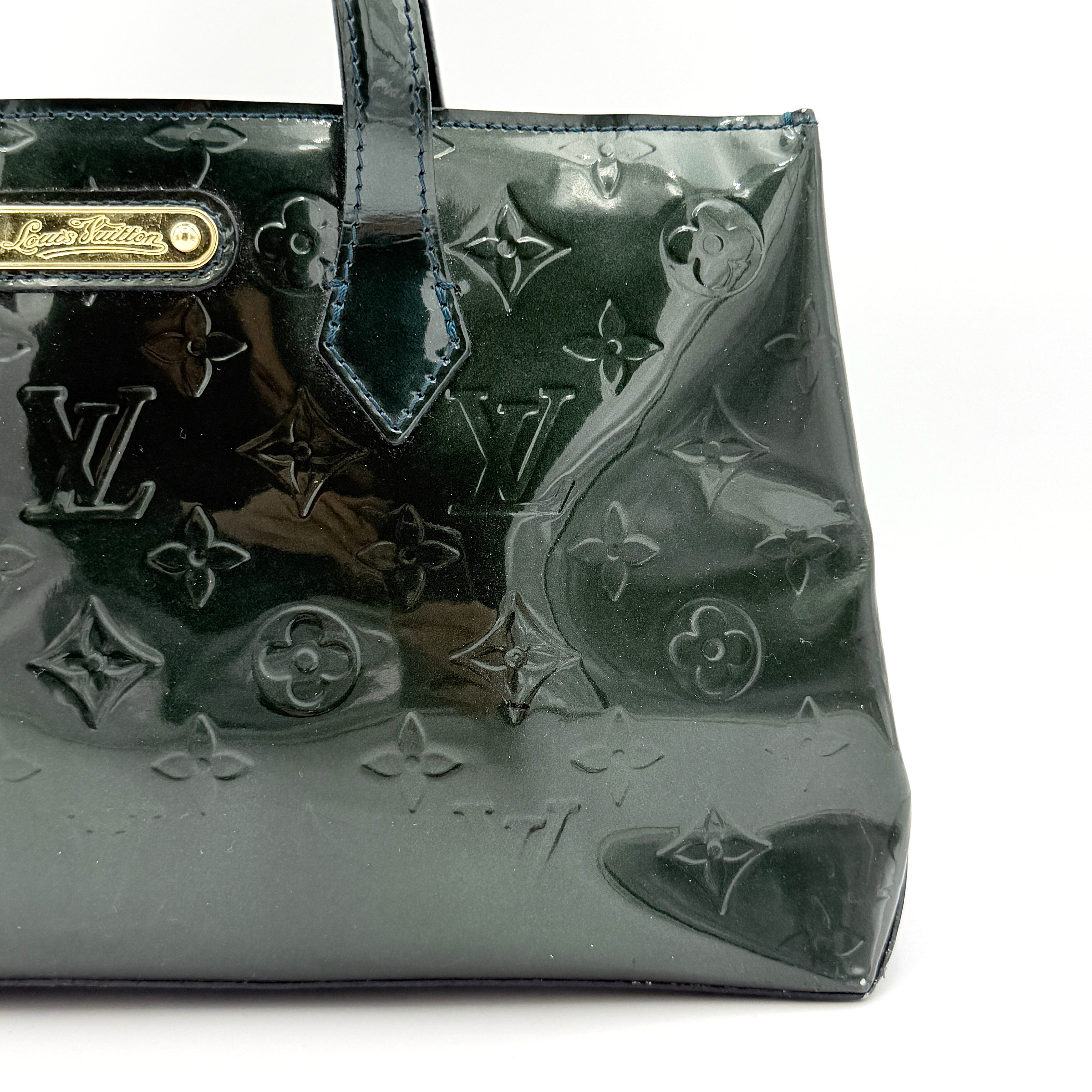 Louis Vuitton Wilshire PM bag in glossy dark green Monogram Vernis patent leather, shown with double top handles and gold-tone nameplate.