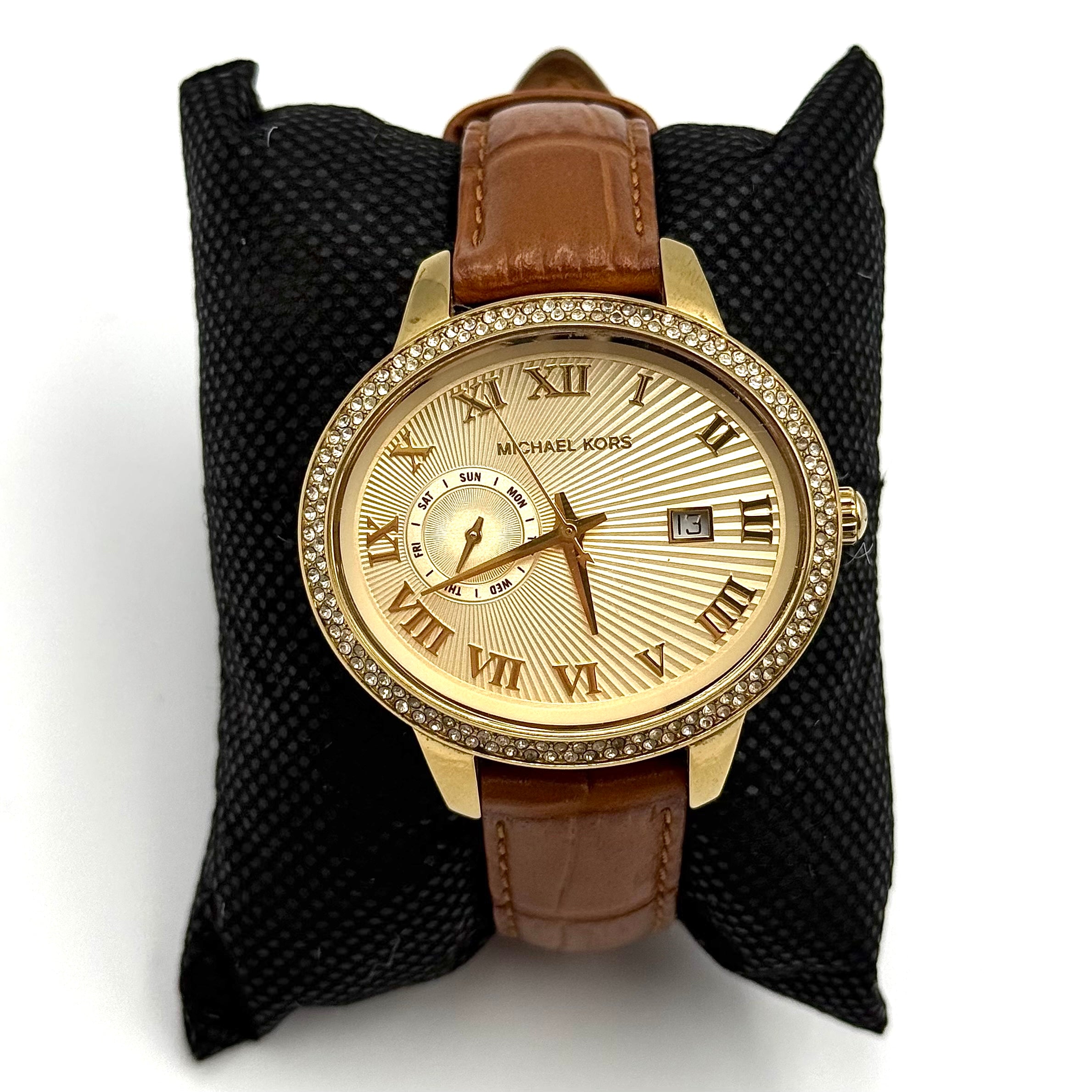 Michael Kors Whitley MK2428 watch with gold dial, crystal bezel and brown leather strap on black cushion
