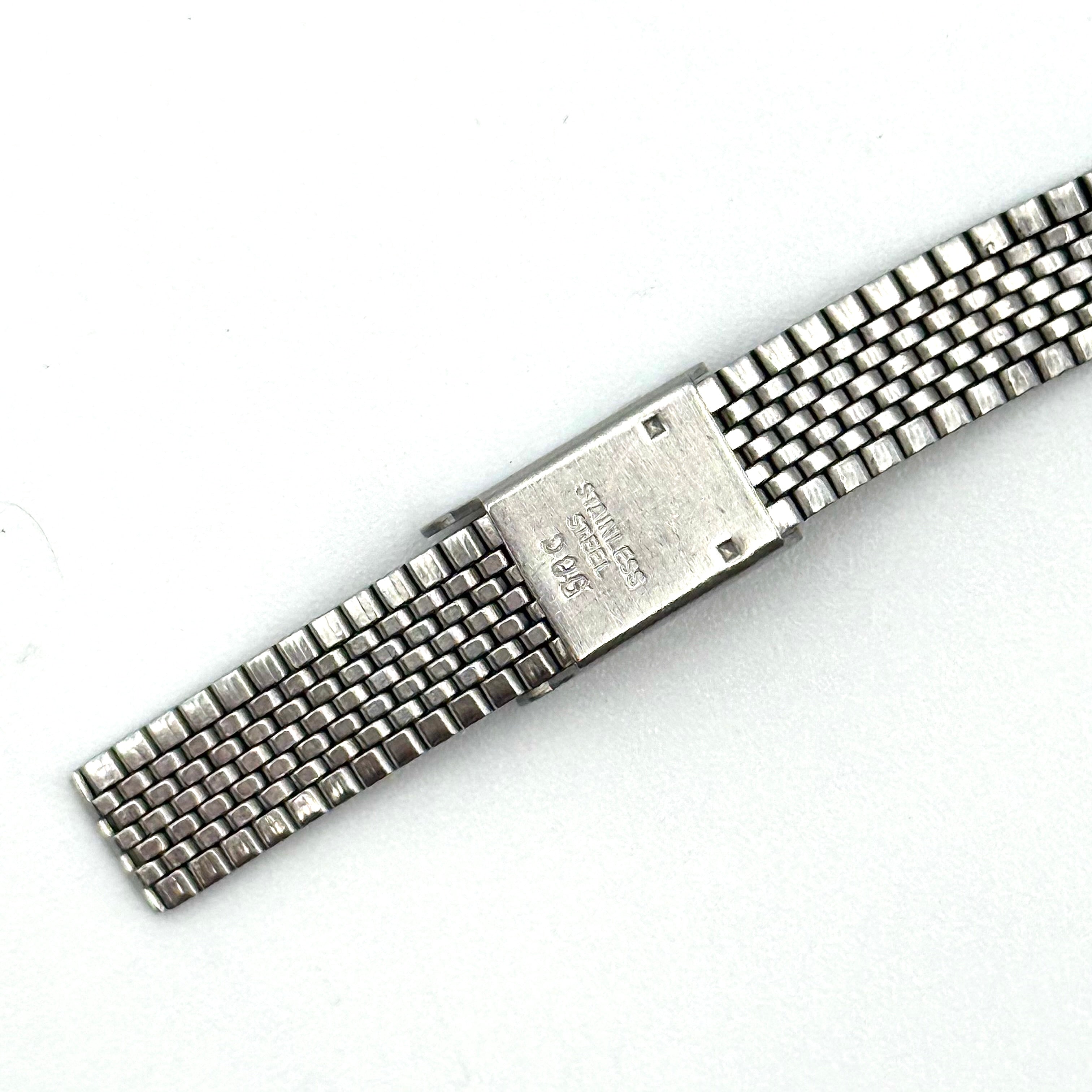Seiko 7903-0030 Quartz stainless steel watch with a white textured dial and matching steel bracelet on a display pillow.