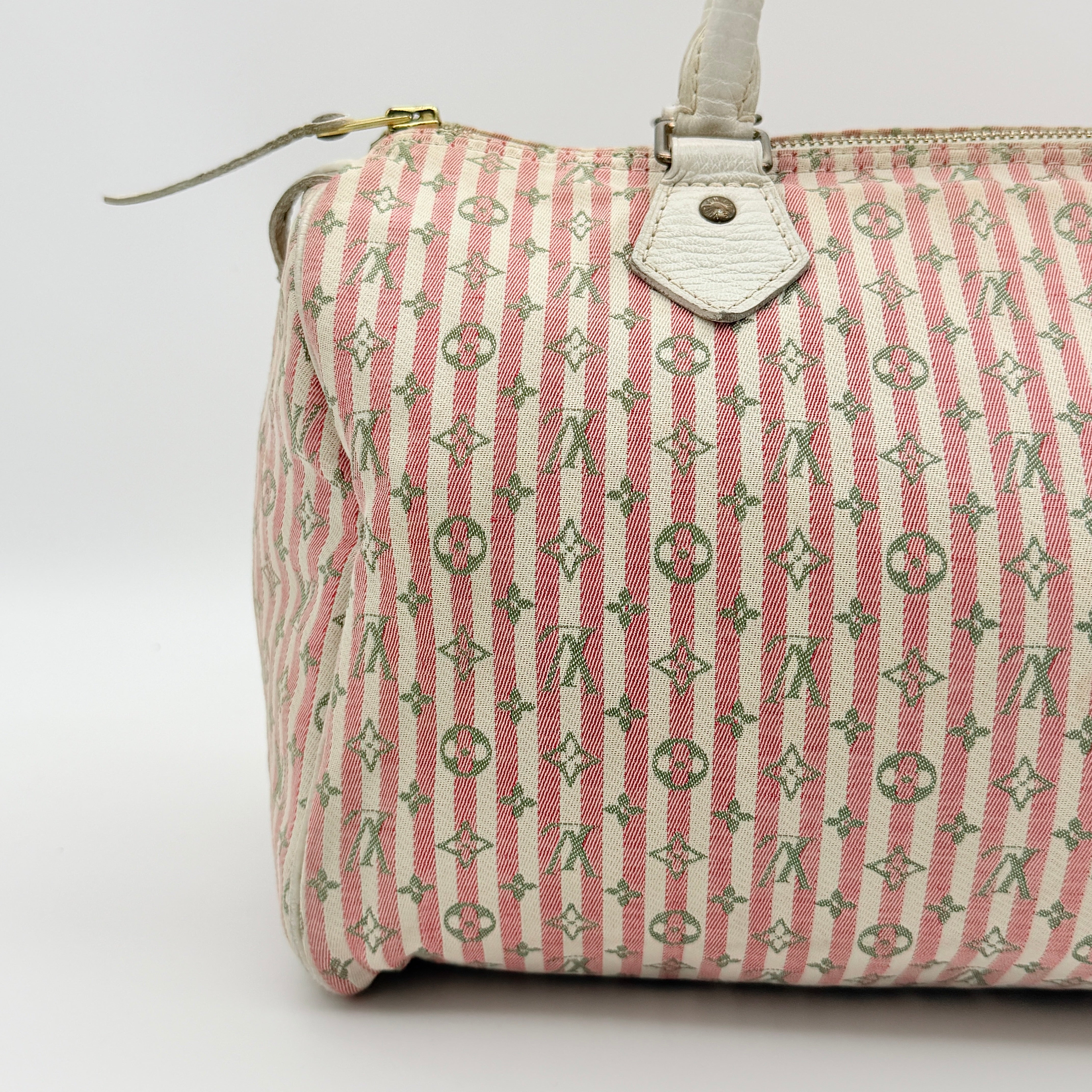 Louis Vuitton Speedy 30 in pink Mini Lin Monogram with cream leather handles and gold-tone zip, displayed on a neutral background.