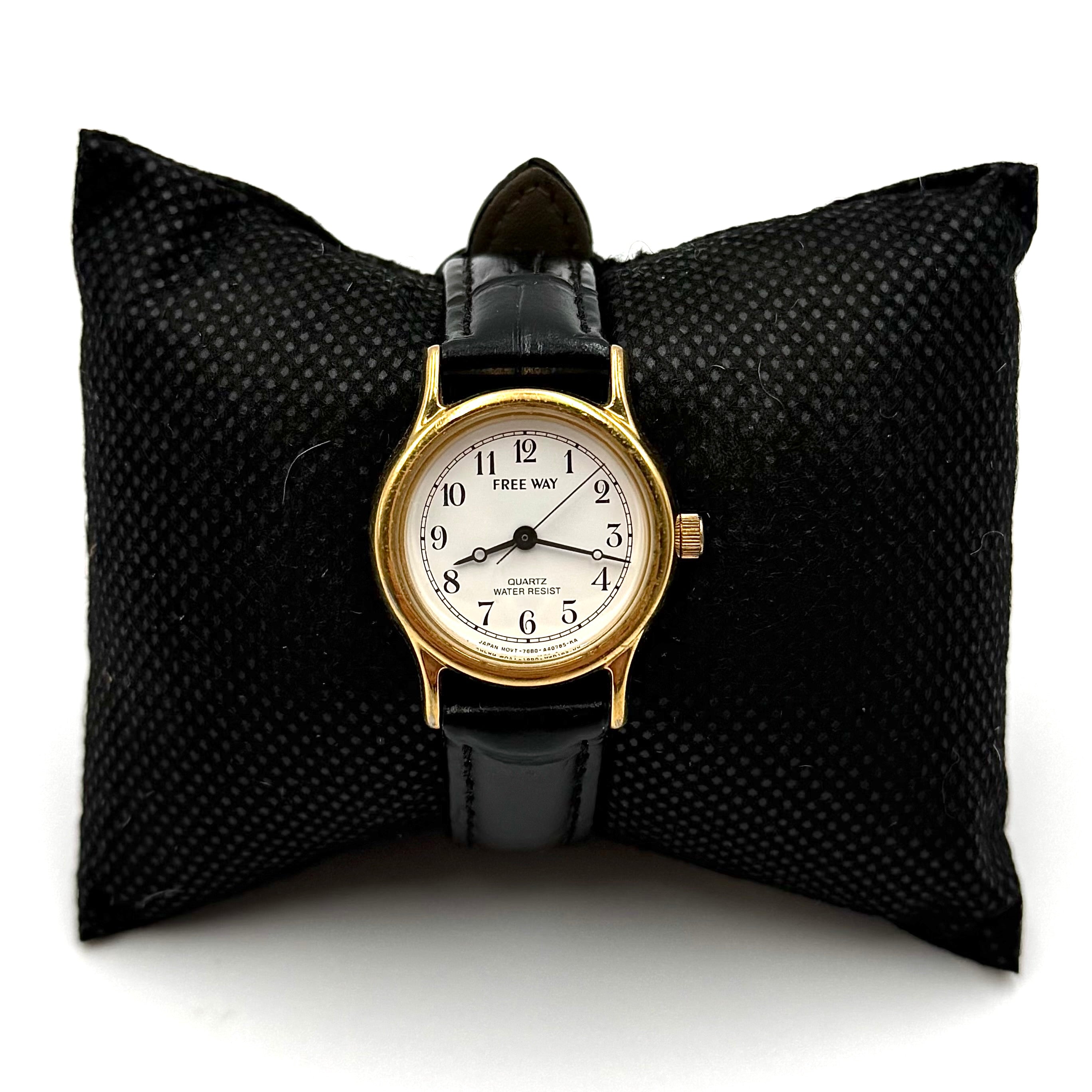 Citizen Freeway Quartz watch with white dial, gold case, and black leather strap displayed on a black cushion.