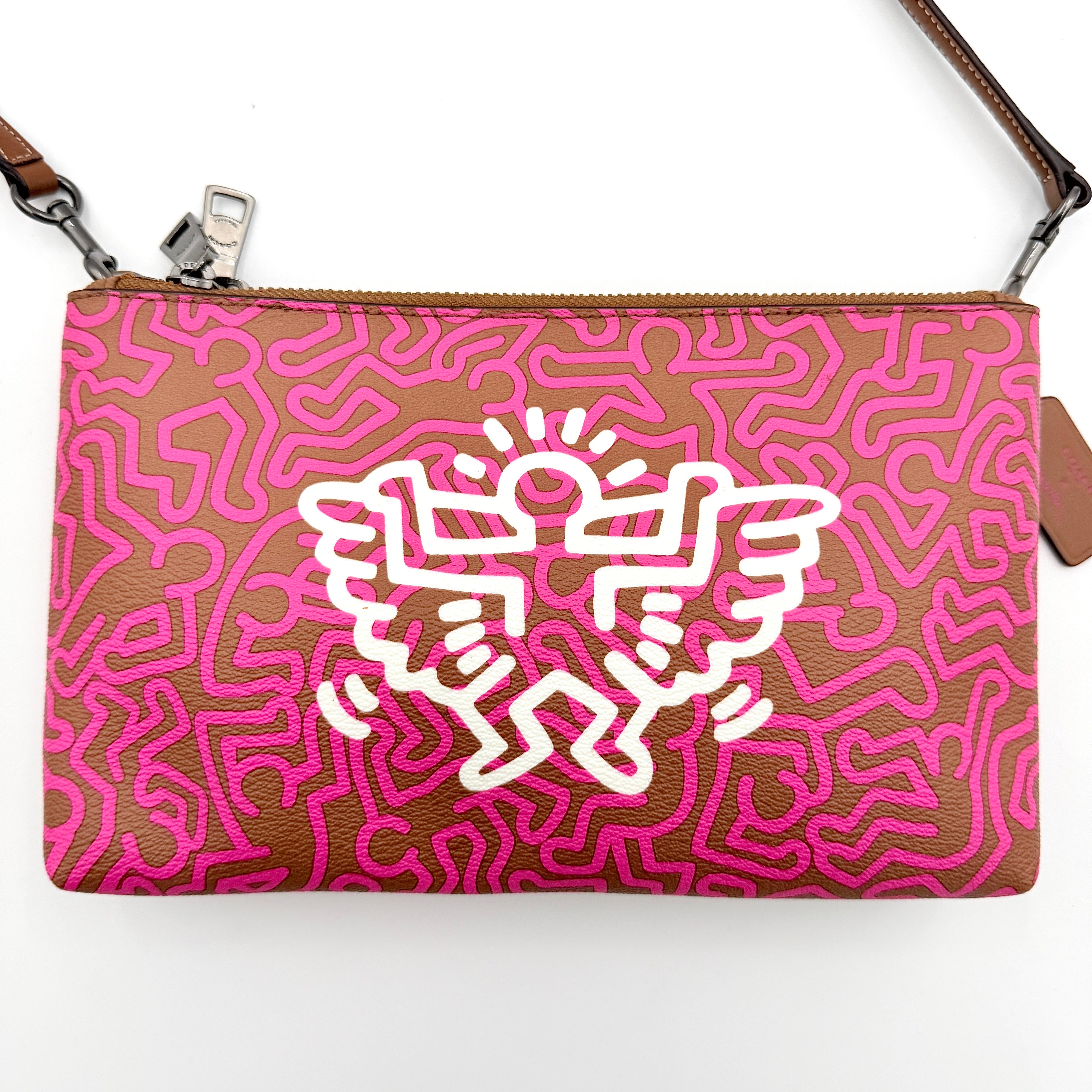 Coach x Keith Haring Lyla Crossbody bag in textured brown leather with bold pink graphic pattern and white artwork, featuring an adjustable strap.