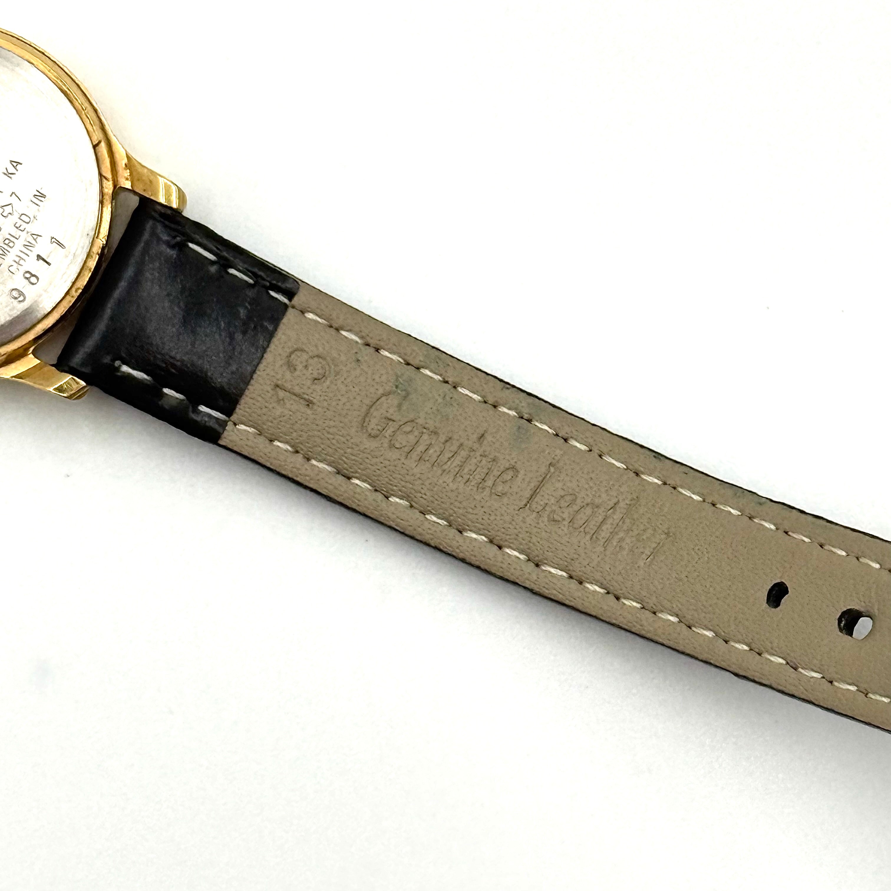Citizen Freeway Quartz watch with white dial, gold case, and black leather strap displayed on a black cushion.