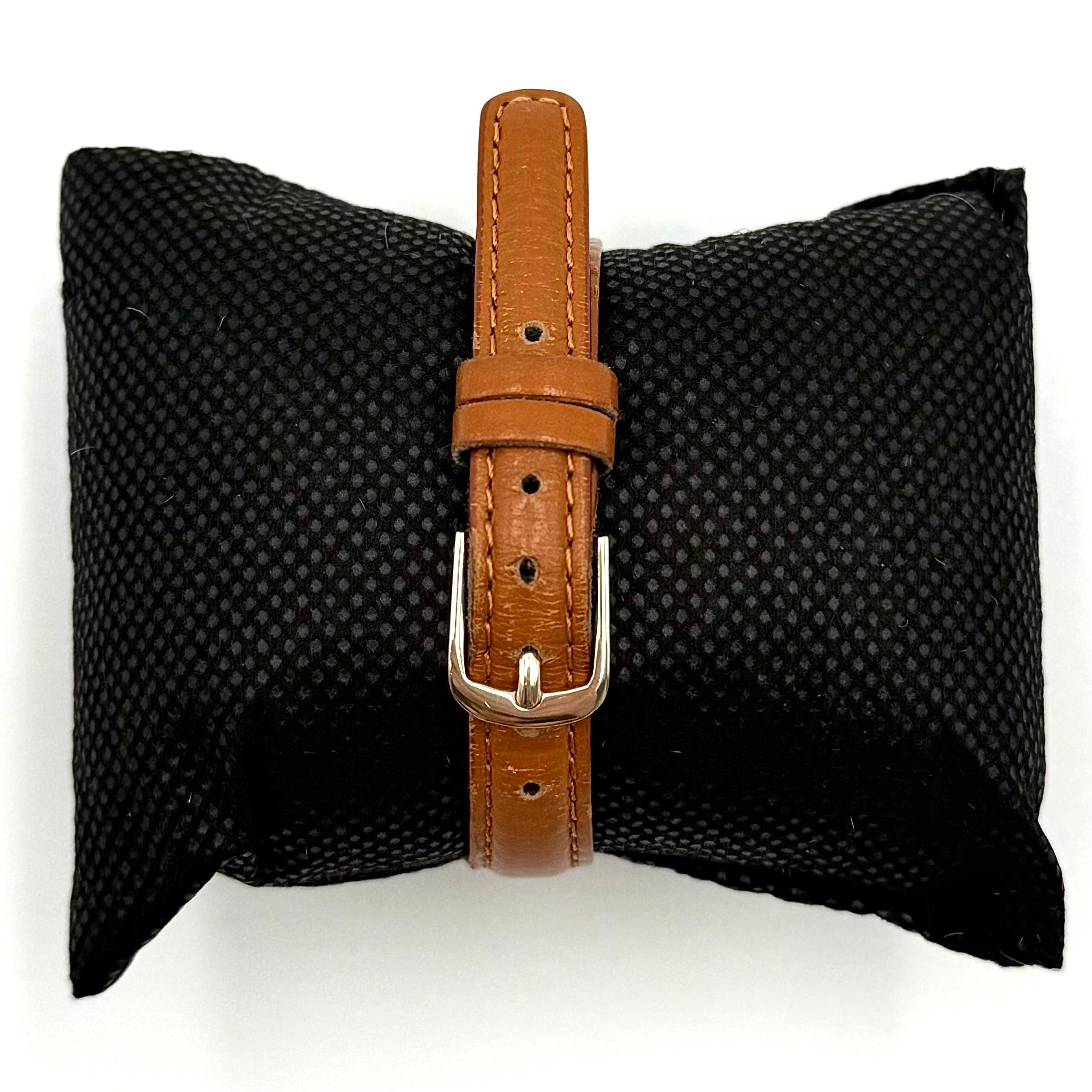 Seiko V701-A110 quartz watch with gold-tone case, cream dial, and brown leather strap on a display pillow.