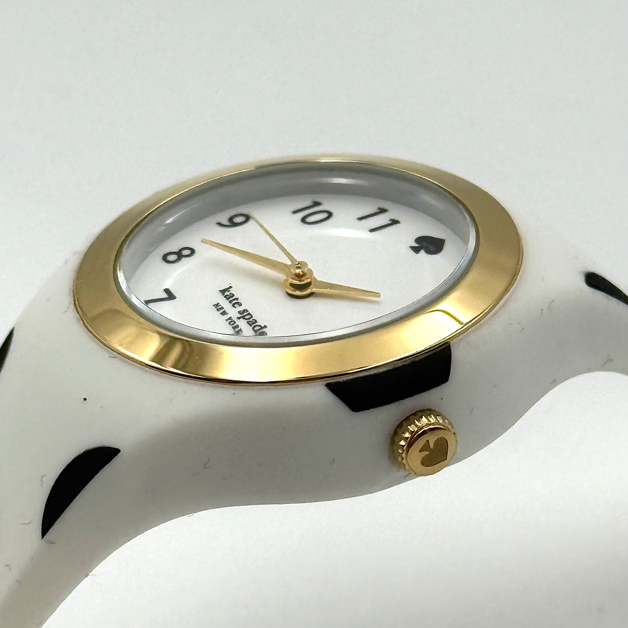 Kate Spade New York Rumsey 0838 silicone watch in white with black polka dots, gold-tone bezel, and white dial displayed on a cushion.
