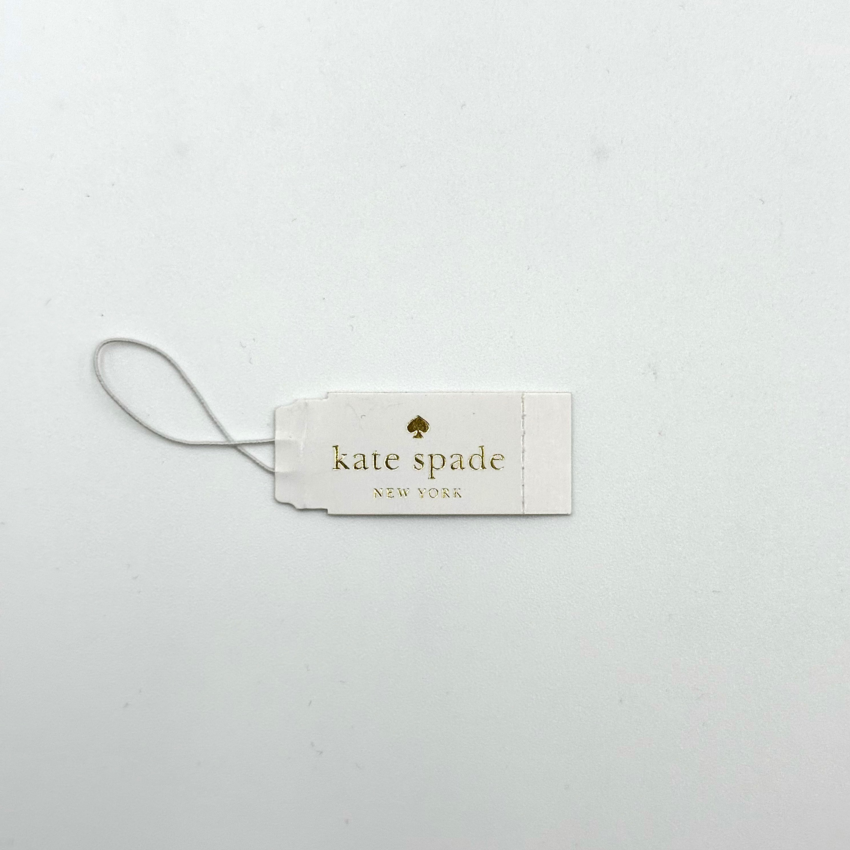 Kate Spade New York Rumsey 0838 silicone watch in white with black polka dots, gold-tone bezel, and white dial displayed on a cushion.