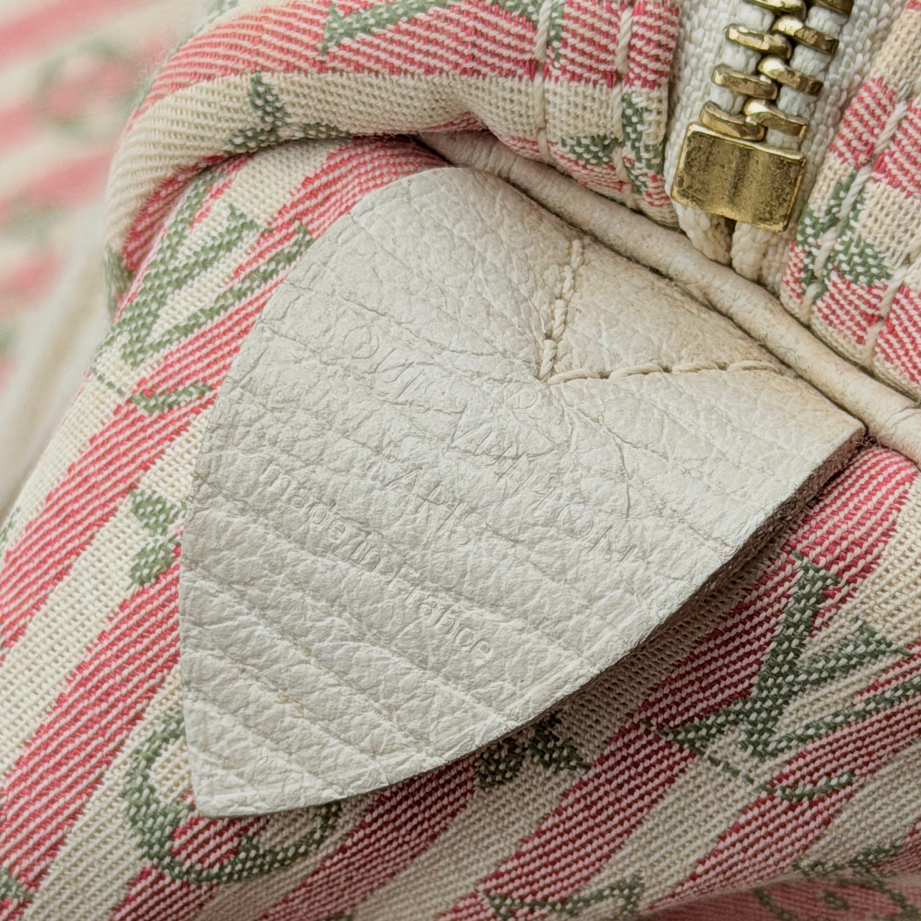 Louis Vuitton Speedy 30 in pink Mini Lin Monogram with cream leather handles and gold-tone zip, displayed on a neutral background.