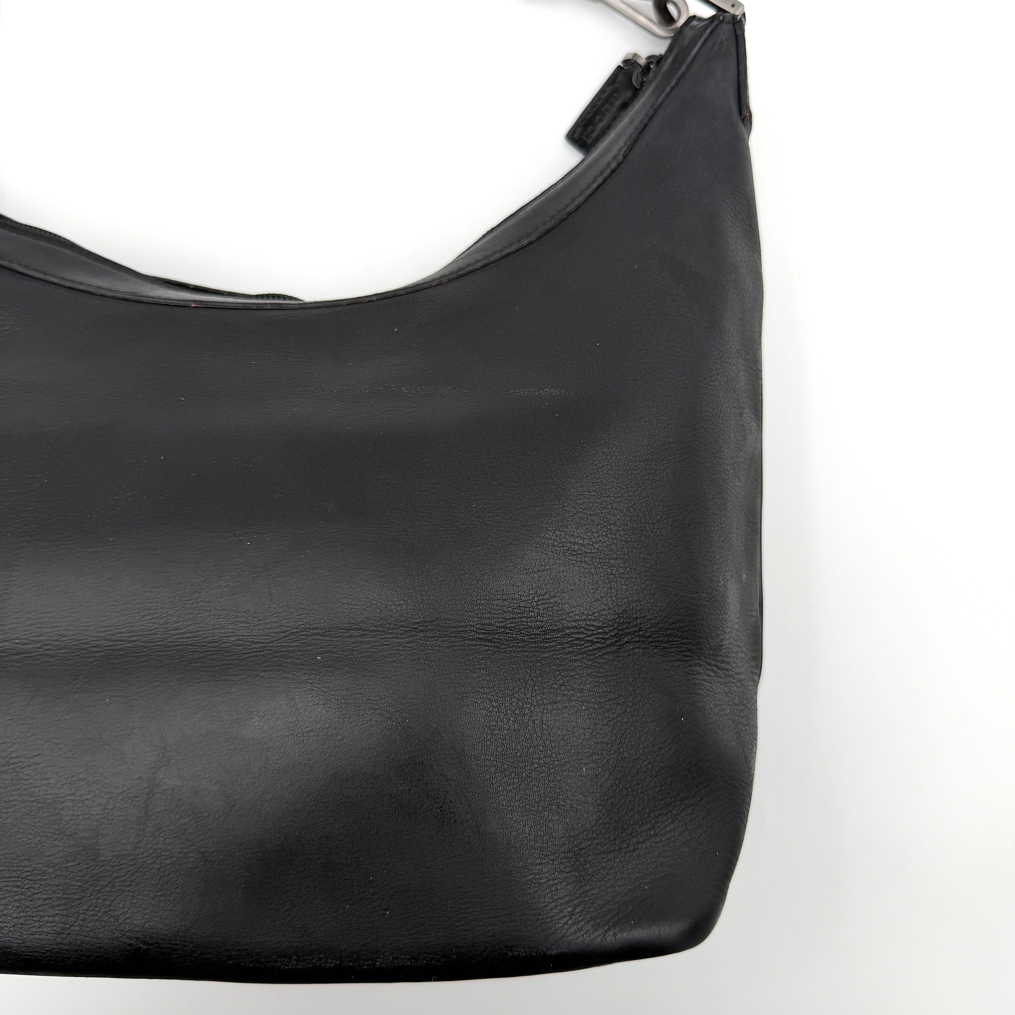 Gucci black leather hobo bag with bamboo handle and silver-tone hardware shown against a white background.