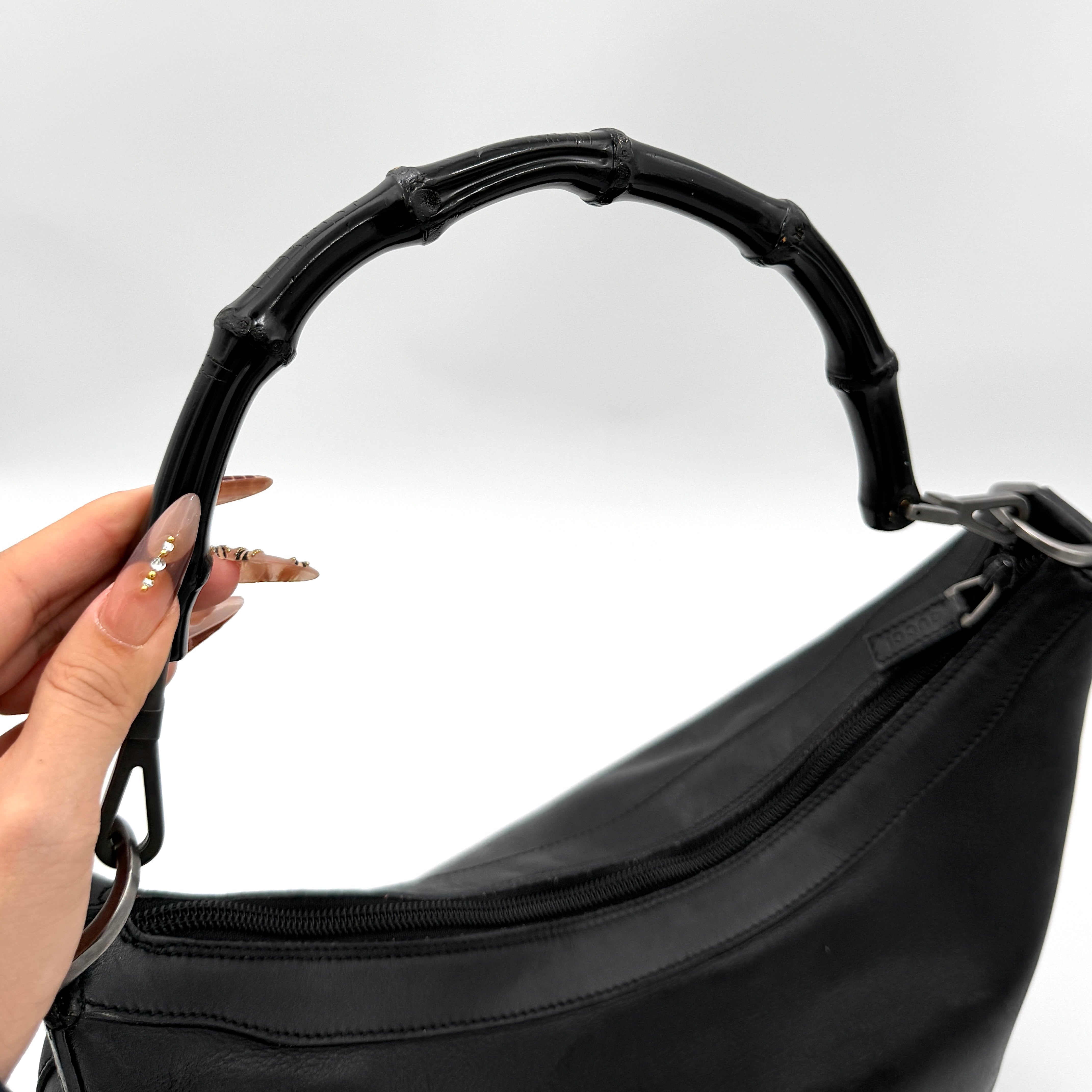 Gucci black leather hobo bag with bamboo handle and silver-tone hardware shown against a white background.