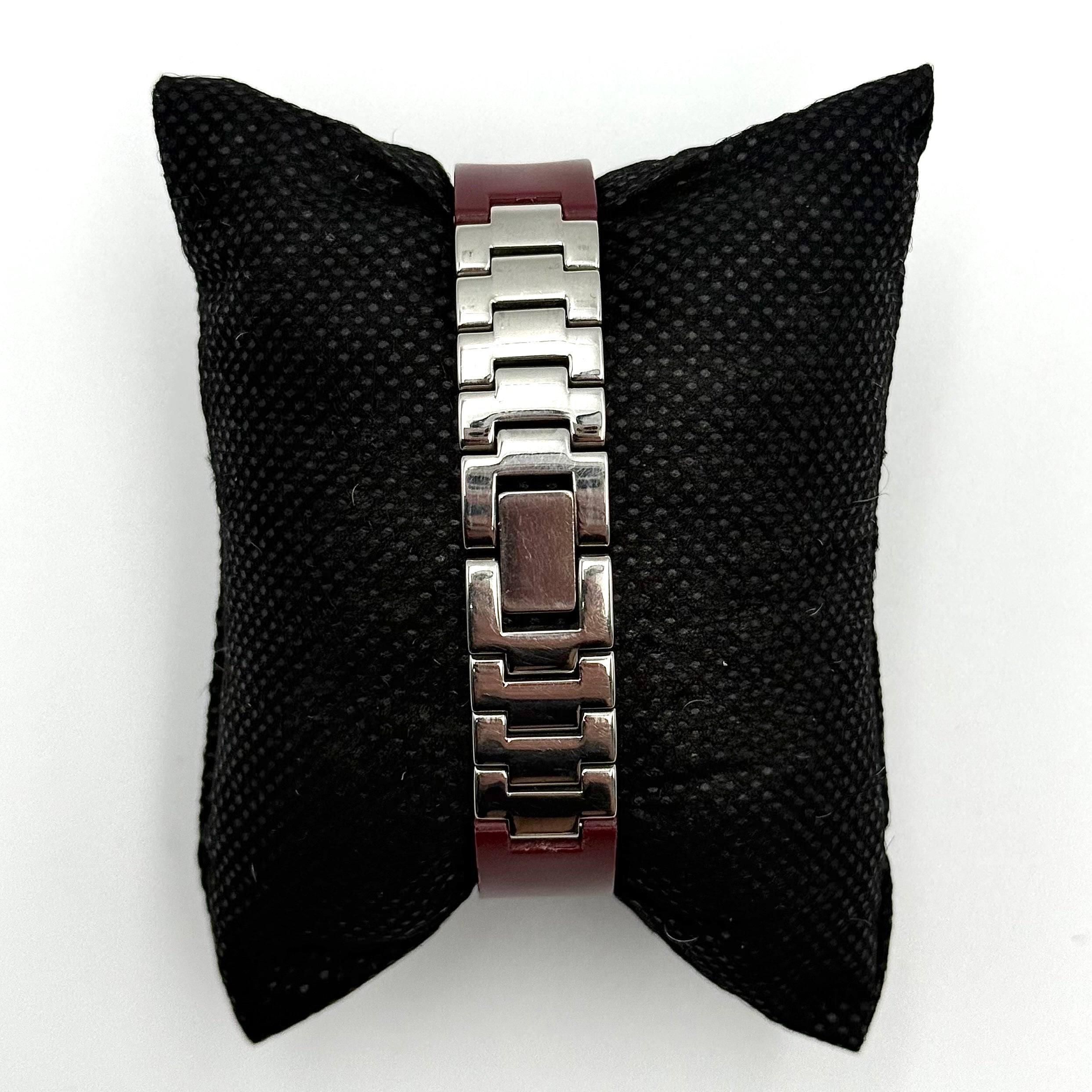 Swatch Irony Lady Angels Call watch in burgundy and silver, presented on a black cushion.