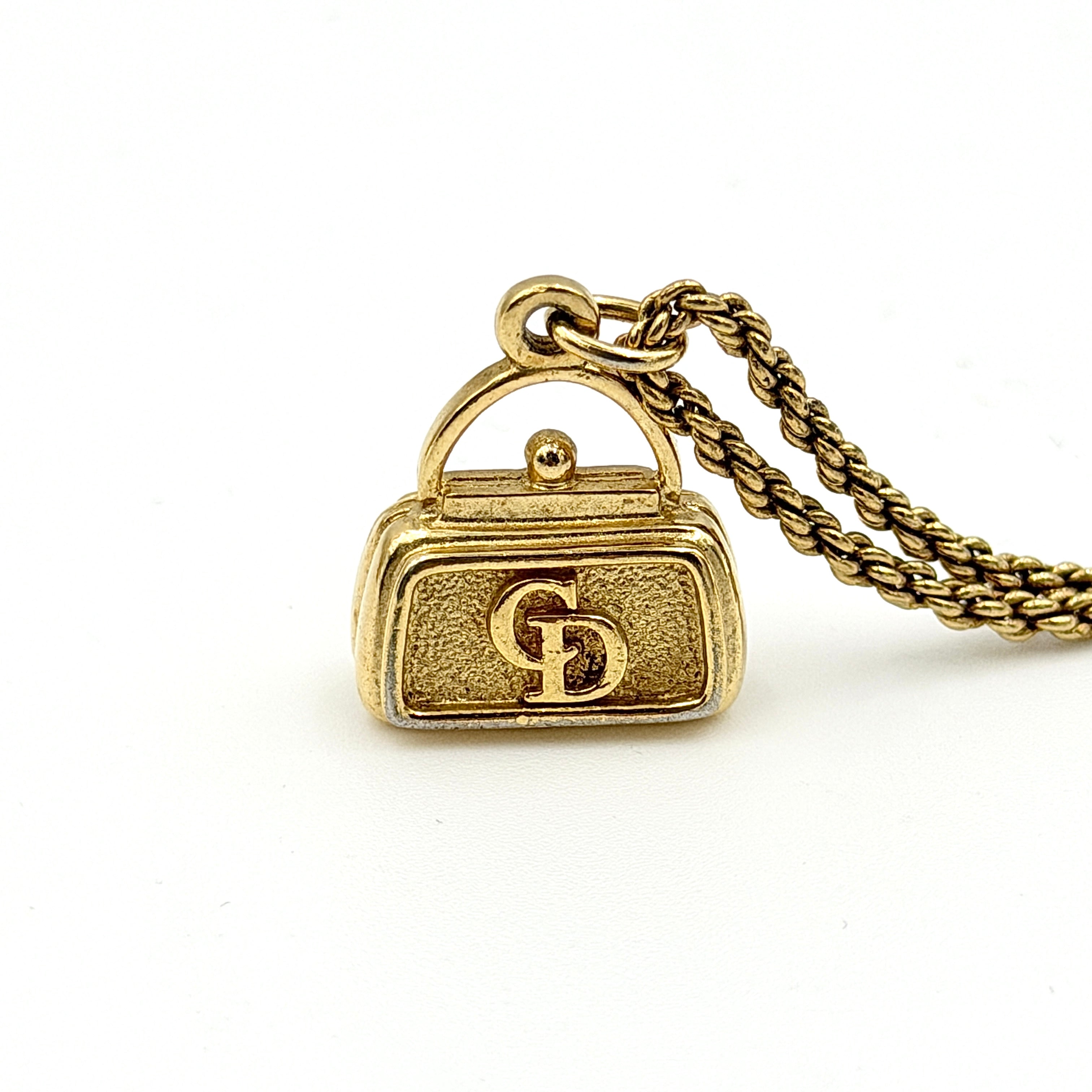 Dior gold necklace with a CD logo handbag pendant on a twisted chain, shown laid flat against a white background.