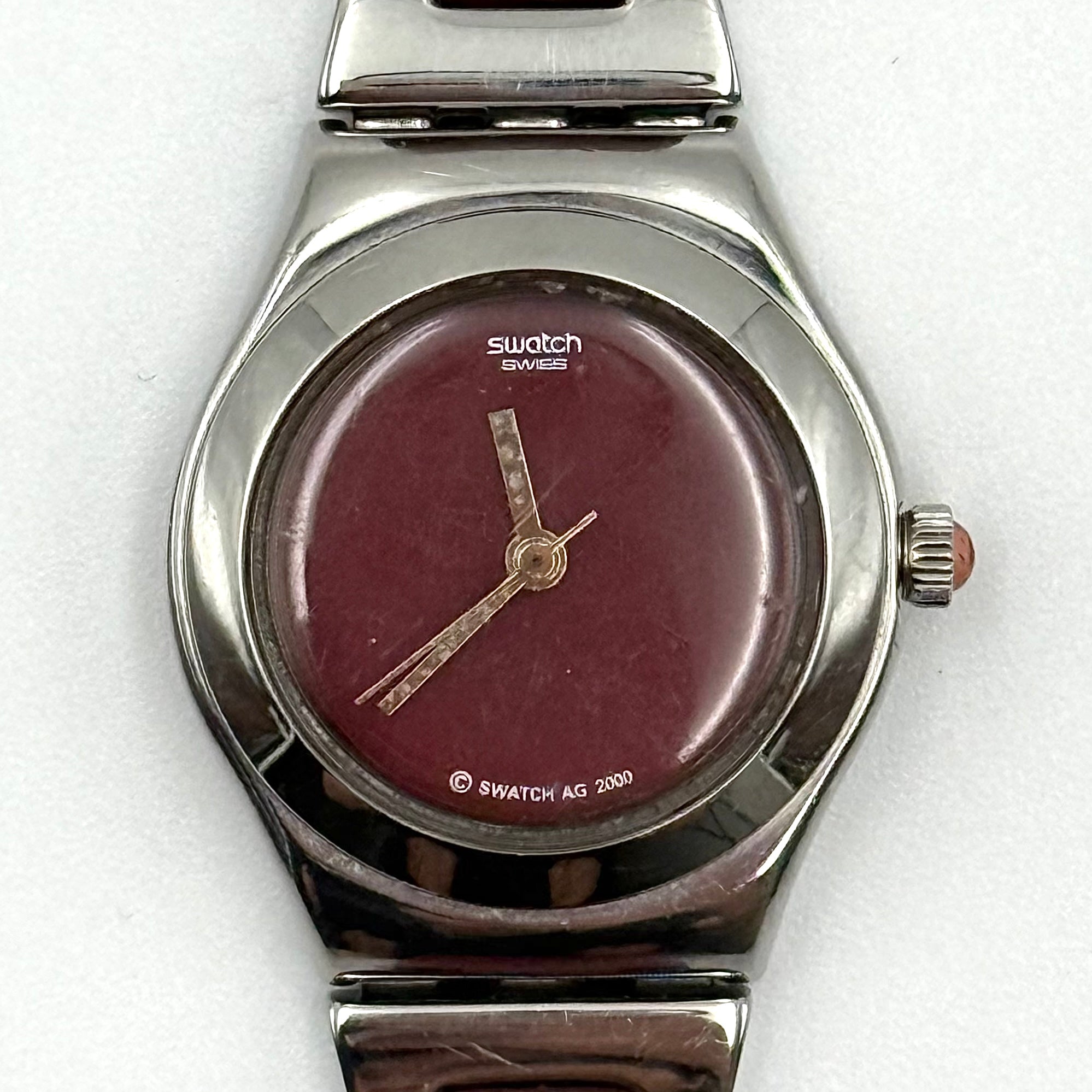 Swatch Irony Lady Angels Call watch in burgundy and silver, presented on a black cushion.
