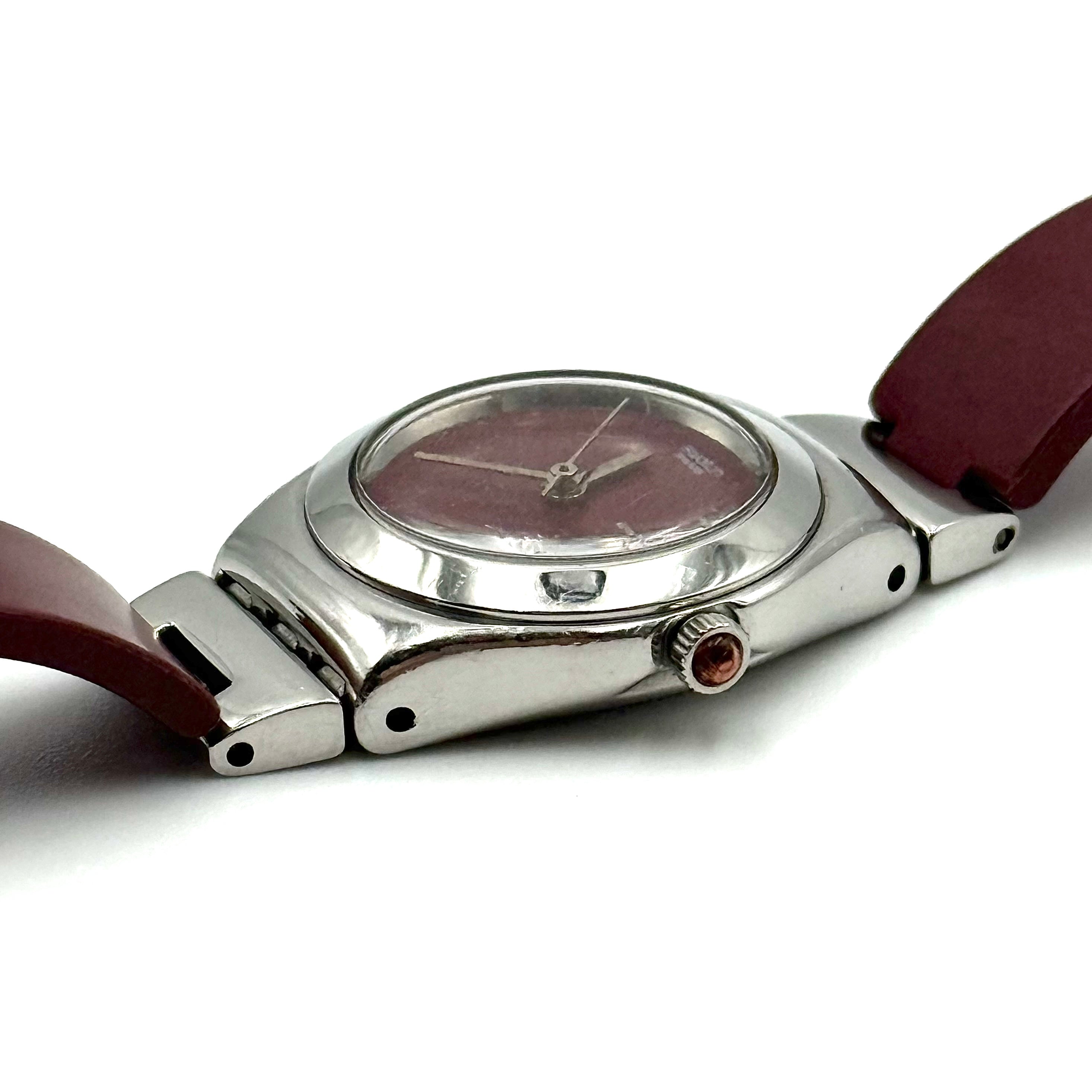 Swatch Irony Lady Angels Call watch in burgundy and silver, presented on a black cushion.
